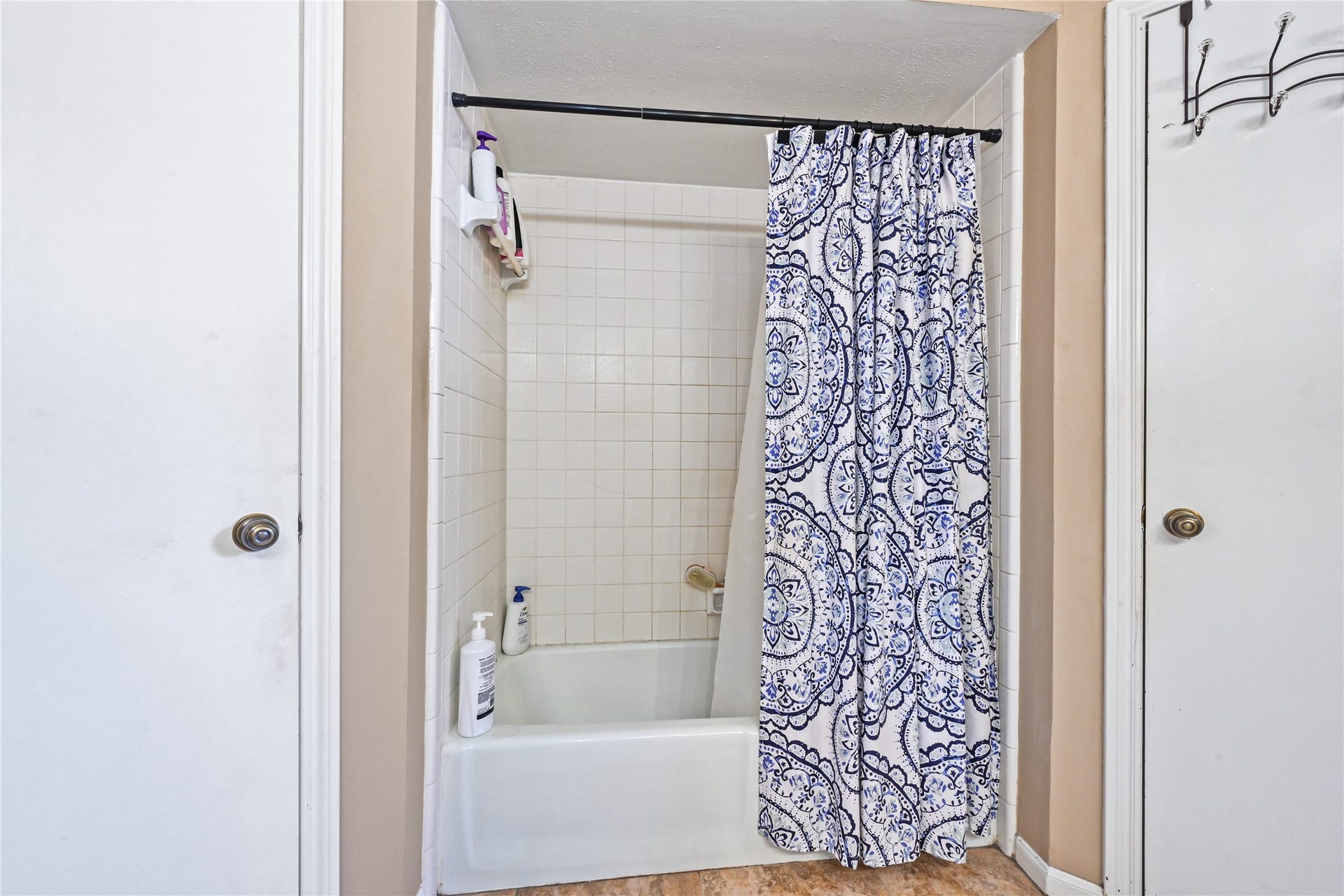 25803 Maplewood Drive, Spring, TX 77386 Cozy bathroom featuring a classic white tiled shower-tub combo with an elegant blue and white patterned curtain, offering a functional and stylish space.