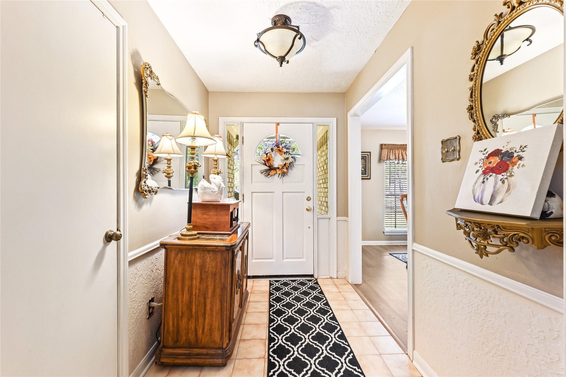 25803 Maplewood Drive, Spring, TX 77386 Charming entryway featuring a welcoming front door with a seasonal wreath, elegant wall mirrors, and a classic wooden console table with stylish decor.
