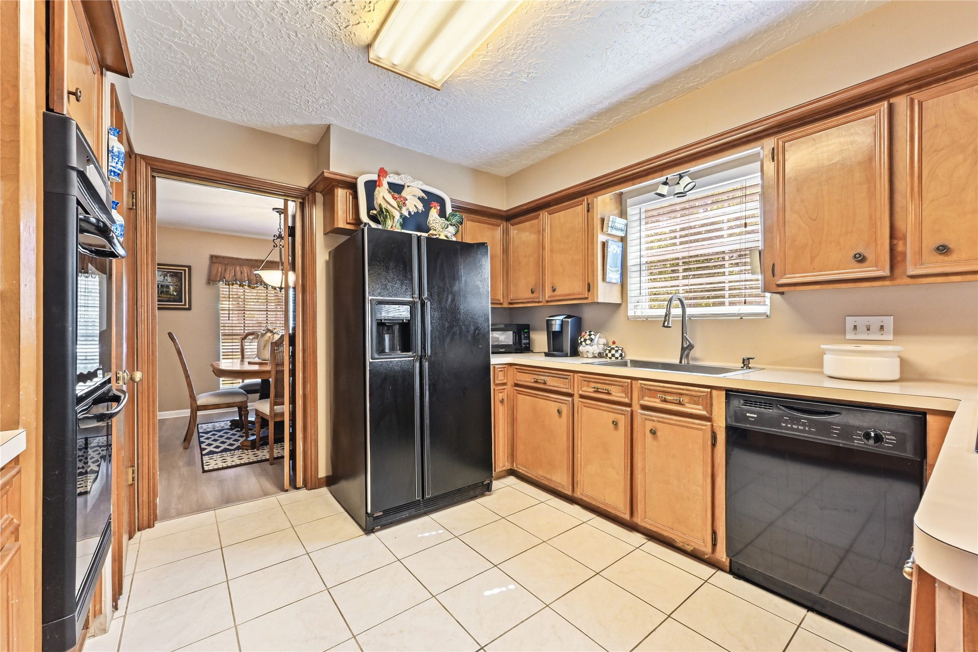 25803 Maplewood Drive, Spring, TX 77386 Charming kitchen with warm wooden cabinetry, sleek black appliances, and a cozy dining area just beyond, perfect for family gatherings.