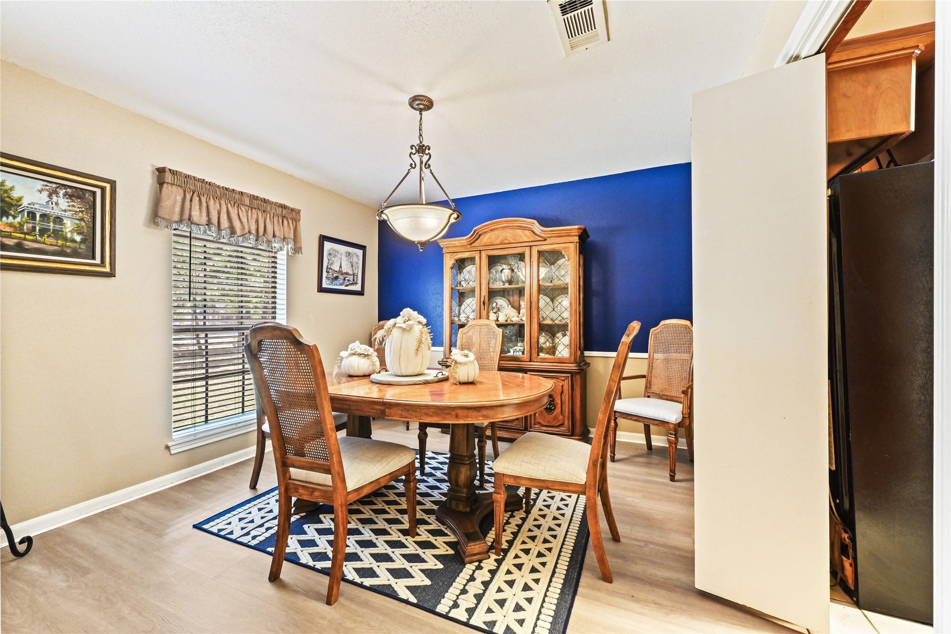 25803 Maplewood Drive, Spring, TX 77386 Charming dining room with a bold blue accent wall, elegant chandelier, and wooden furniture, creating a cozy and inviting atmosphere perfect for family gatherings.