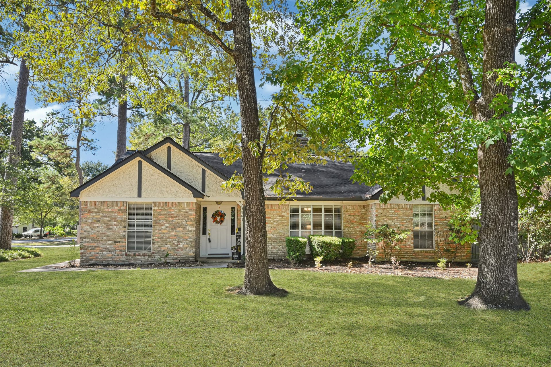 25803 Maplewood Drive, Spring, TX 77386 Charming brick home nestled among mature trees, offering a spacious lawn and inviting curb appeal.