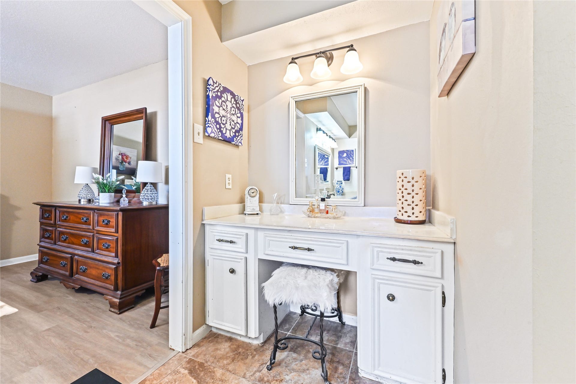 25803 Maplewood Drive, Spring, TX 77386 Charming vanity area with a well-lit mirror, elegant white cabinetry, and a cozy seating nook, seamlessly adjoining a warmly furnished bedroom.