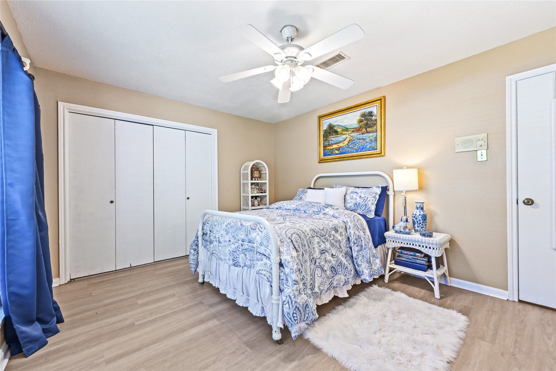 25803 Maplewood Drive, Spring, TX 77386 Charming bedroom with elegant blue and white decor, featuring a cozy bed, ceiling fan, ample closet space, and warm wood flooring.
