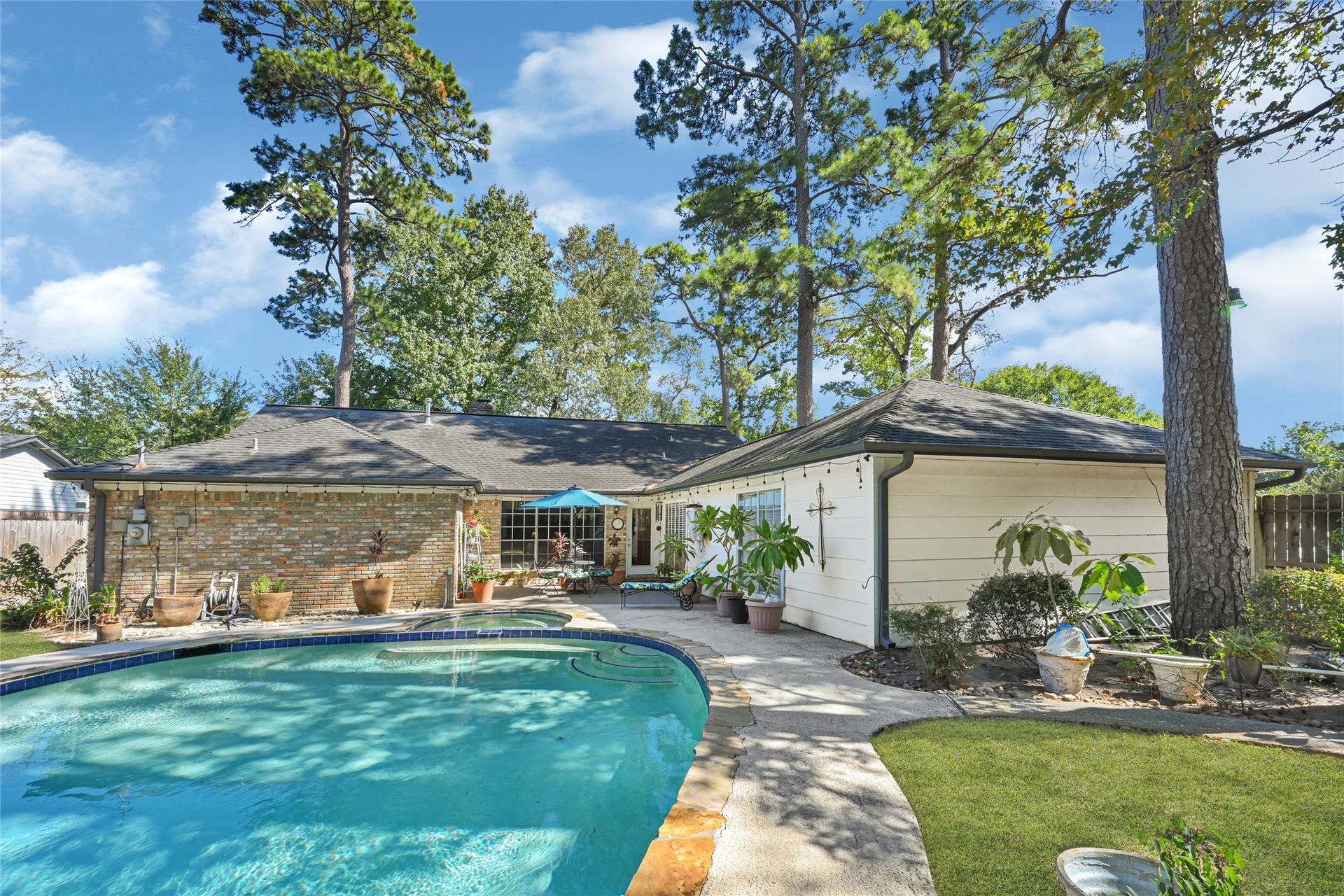 25803 Maplewood Drive, Spring, TX 77386 Charming home with a spacious backyard featuring a sparkling pool surrounded by lush greenery and mature trees, perfect for relaxation and entertaining.