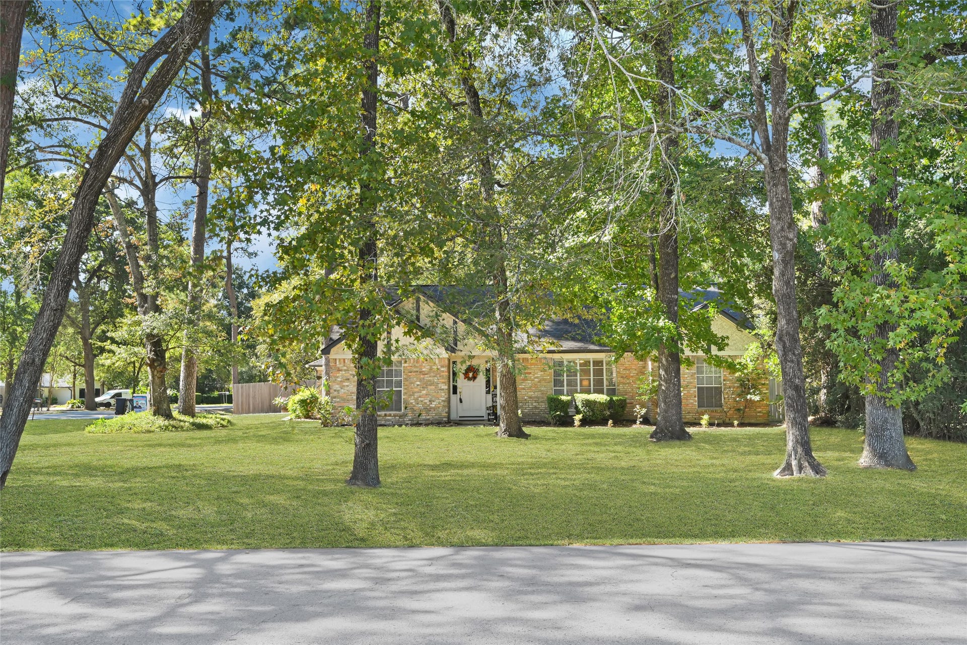 25803 Maplewood Drive, Spring, TX 77386 Charming brick home nestled among mature trees, offering a serene and spacious front yard.