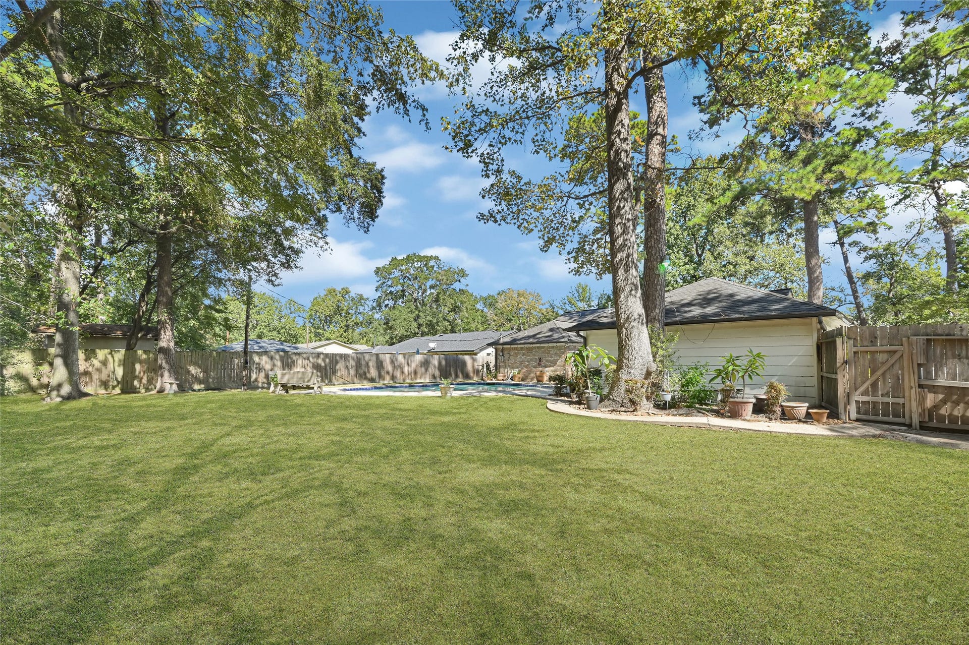 25803 Maplewood Drive, Spring, TX 77386 Expansive backyard featuring lush green lawn, mature trees, and a sparkling pool, perfect for outdoor relaxation and entertainment.