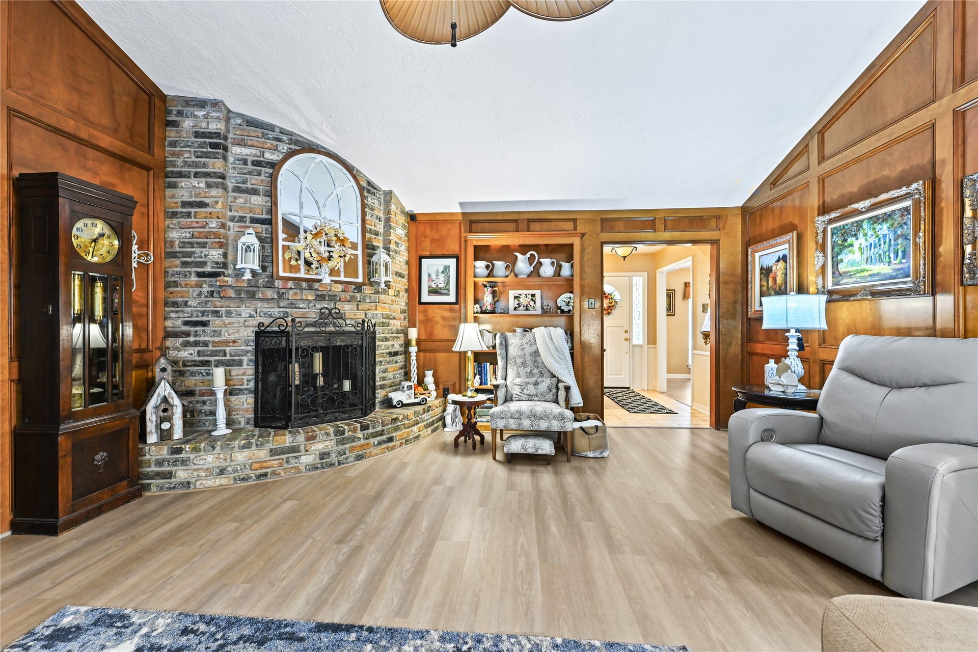 25803 Maplewood Drive, Spring, TX 77386 Cozy living room with rich wood paneling and a striking brick fireplace, complemented by elegant decor and comfortable seating.