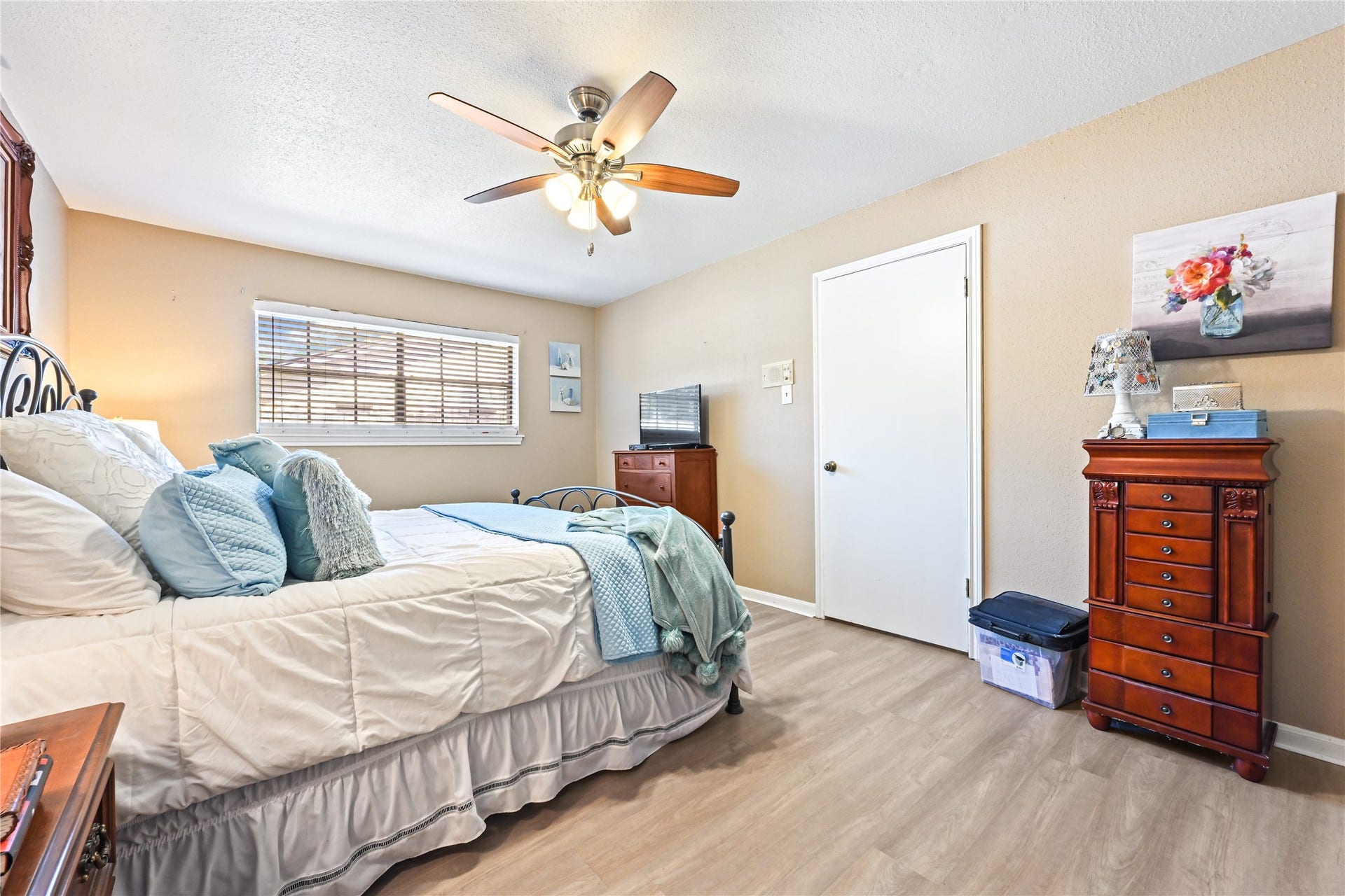 25803 Maplewood Drive, Spring, TX 77386 Spacious bedroom with warm, neutral tones features a cozy bed with elegant iron headboard, a ceiling fan for comfort, and ample natural light from a large window.