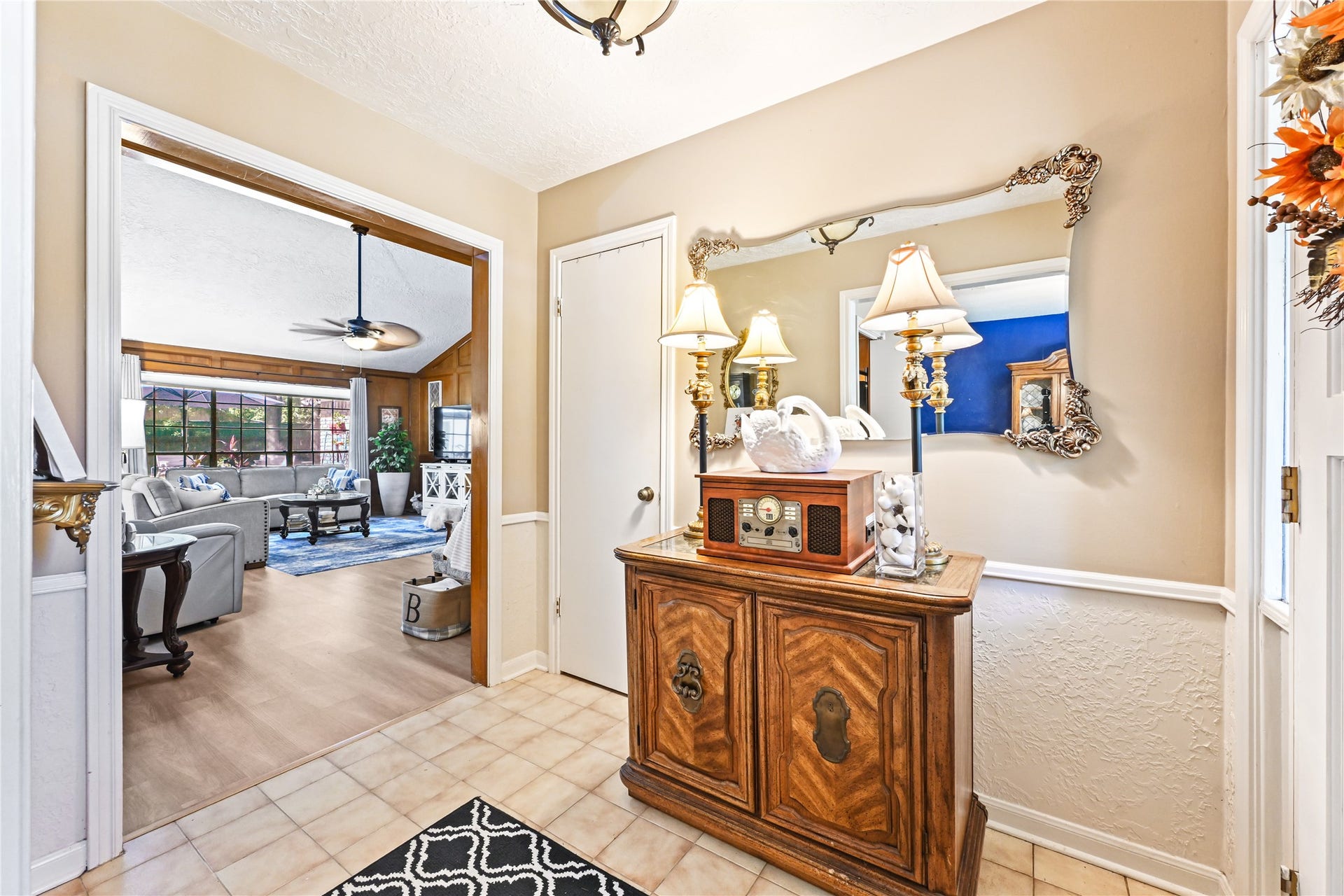 25803 Maplewood Drive, Spring, TX 77386 Charming entryway with elegant decor leads to a spacious living room featuring a cozy seating area, large windows, and a ceiling fan.