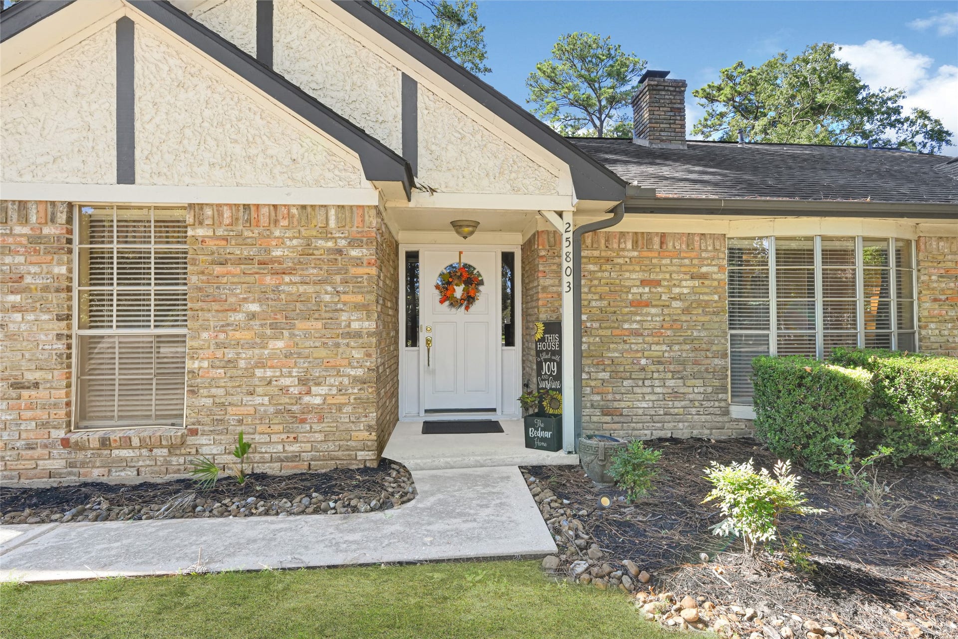 25803 Maplewood Drive, Spring, TX 77386 Charming brick home with a welcoming front porch, accented by a bright white door and lush greenery, offering great curb appeal.
