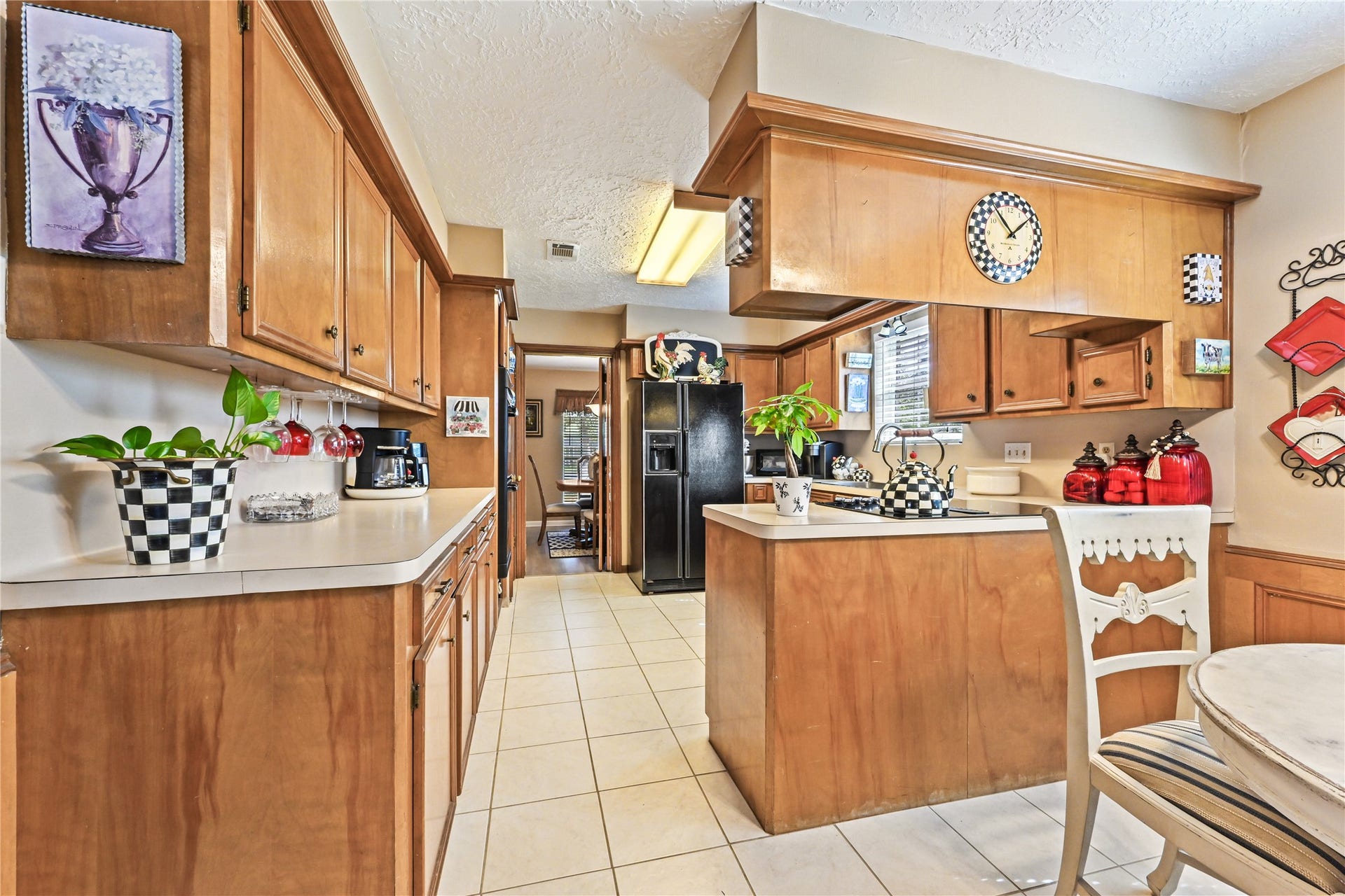 25803 Maplewood Drive, Spring, TX 77386 Charming kitchen with warm wood cabinetry, spacious countertops, and stylish checkered accents, featuring modern appliances and a cozy breakfast nook.