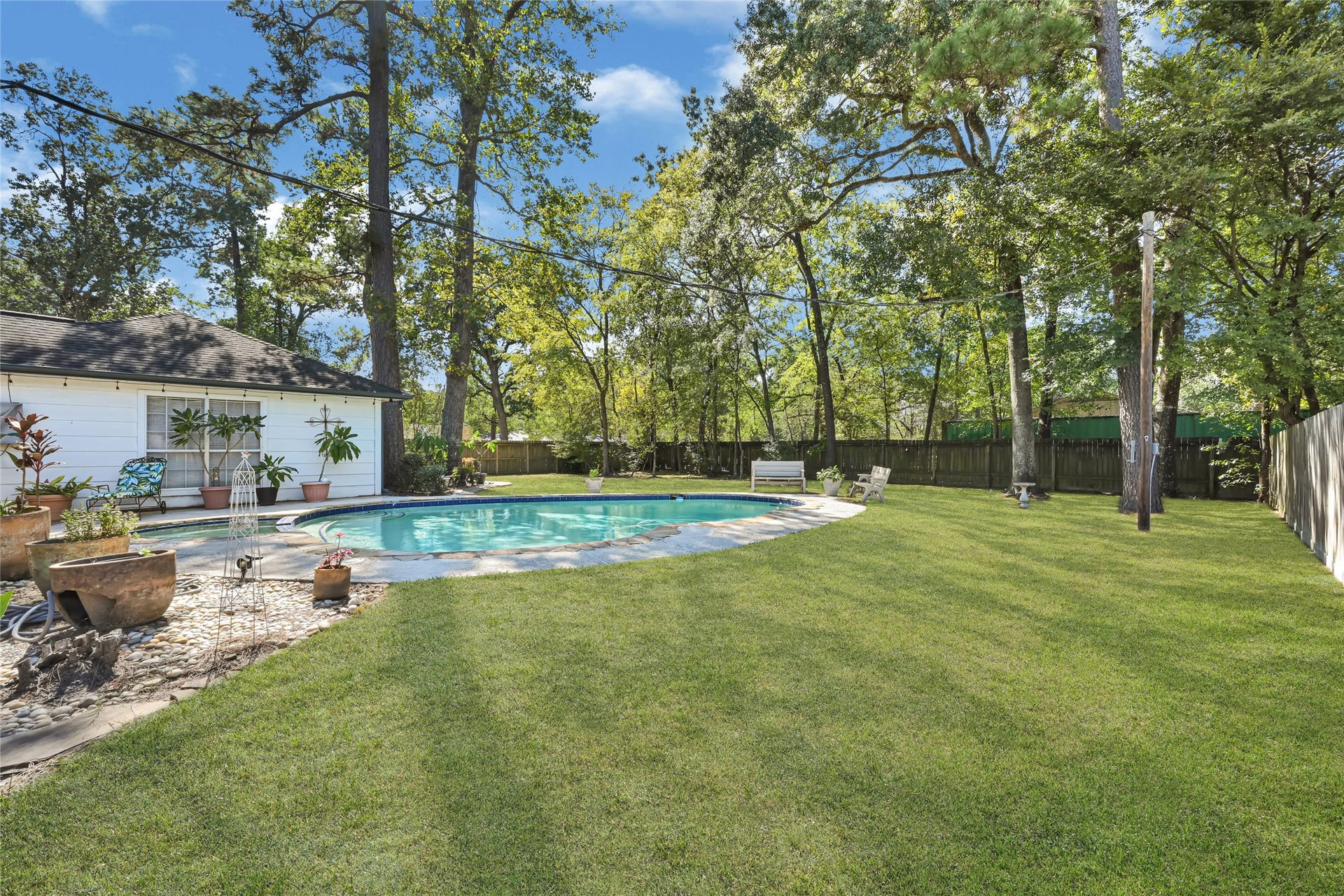 25803 Maplewood Drive, Spring, TX 77386 Spacious backyard oasis with a sparkling pool surrounded by lush greenery, perfect for relaxation and outdoor entertaining.