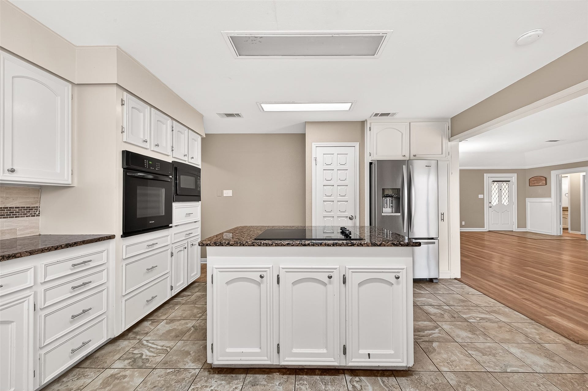 5607 Avenue M 1/2, Santa Fe, TX 77510 Kitchen with modern appliances, granite countertops, and ample white cabinetry. Open layout flows into a bright living area with wood flooring. Ideal for entertaining and family living.