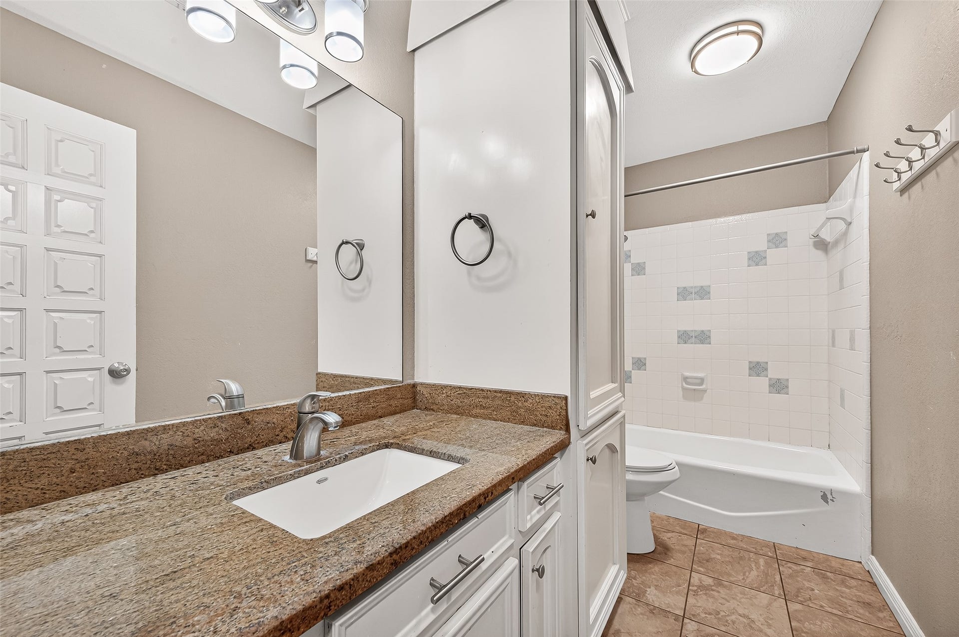 5607 Avenue M 1/2, Santa Fe, TX 77510 This bathroom features a granite countertop with a modern sink, ample cabinet storage, and a full bathtub with a tiled shower. The neutral color palette and bright lighting create a clean and inviting atmosphere.