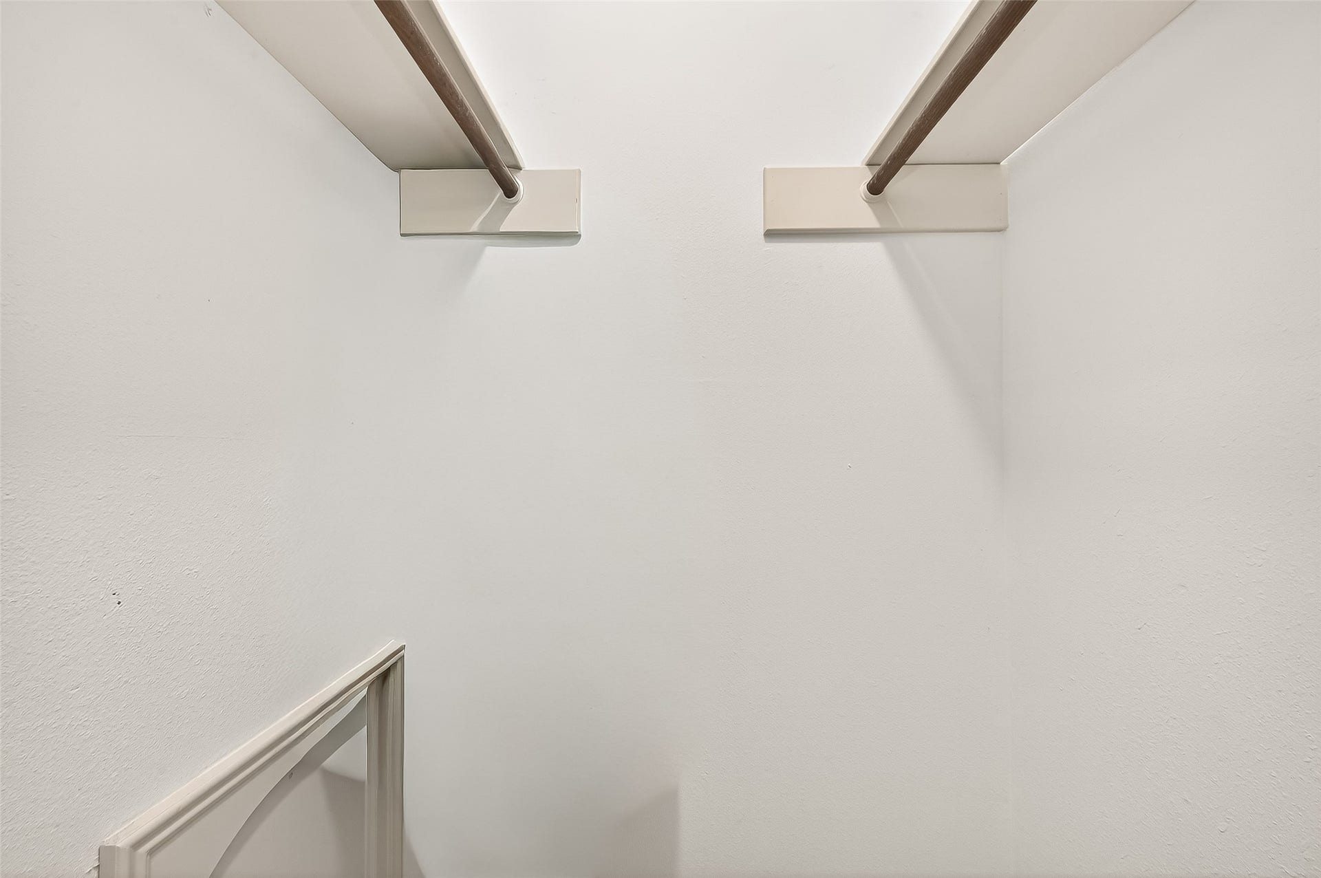 5607 Avenue M 1/2, Santa Fe, TX 77510 This image shows a simple, white walk-in closet with dual hanging rods, offering ample space for clothing storage.