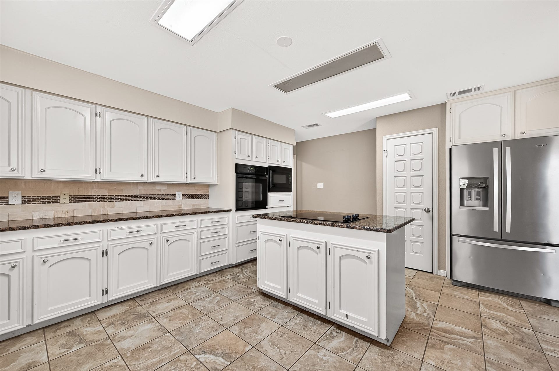 5607 Avenue M 1/2, Santa Fe, TX 77510 Kitchen with modern appliances, ample white cabinetry, and a central island. Features include tiled flooring, granite countertops, and recessed lighting for a bright, welcoming atmosphere.