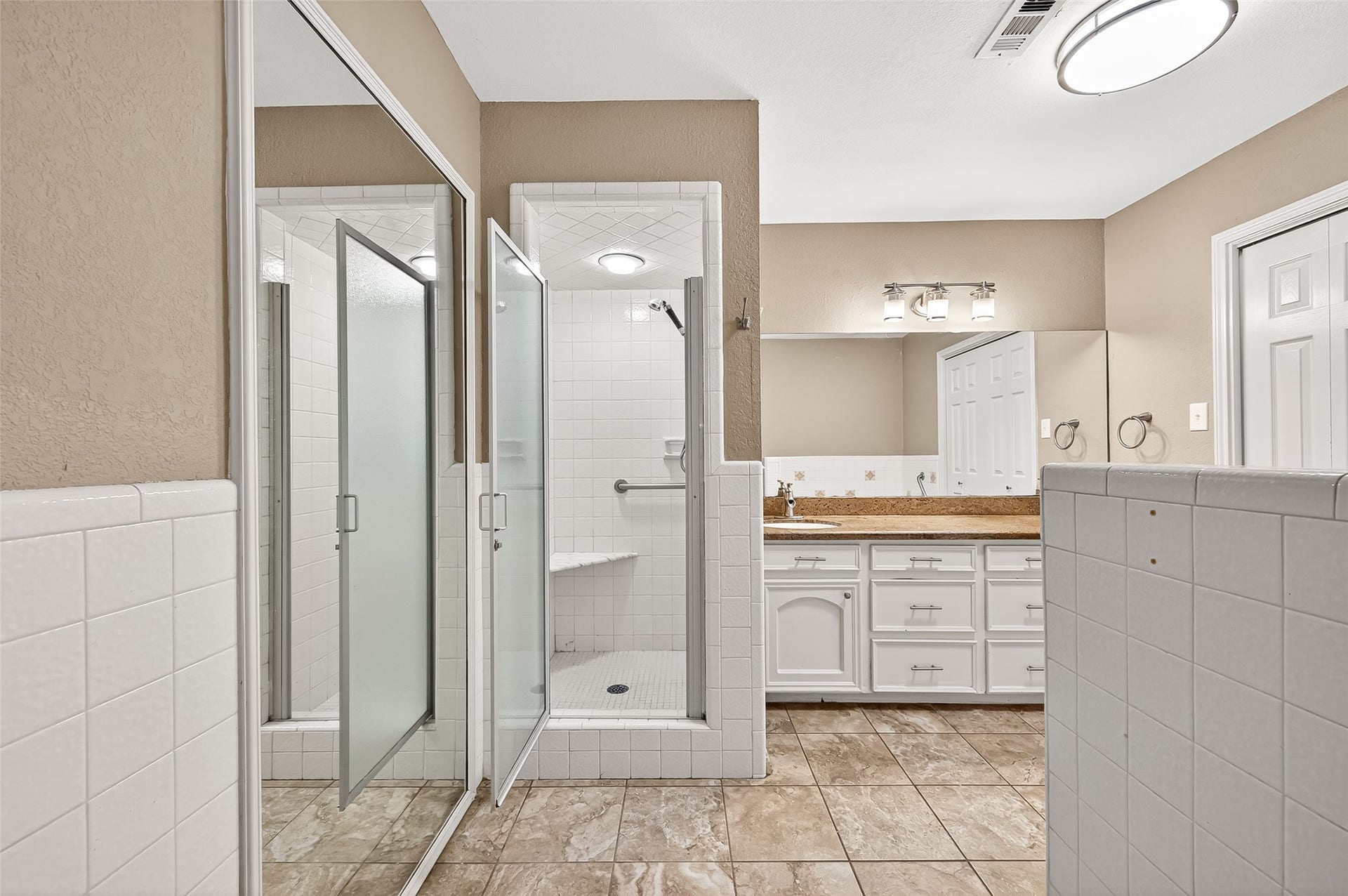 5607 Avenue M 1/2, Santa Fe, TX 77510 This bathroom features a spacious walk-in shower with glass doors, a large vanity with ample storage, and a bright, well-lit mirror. The neutral tones and tiled flooring create a clean, modern look.