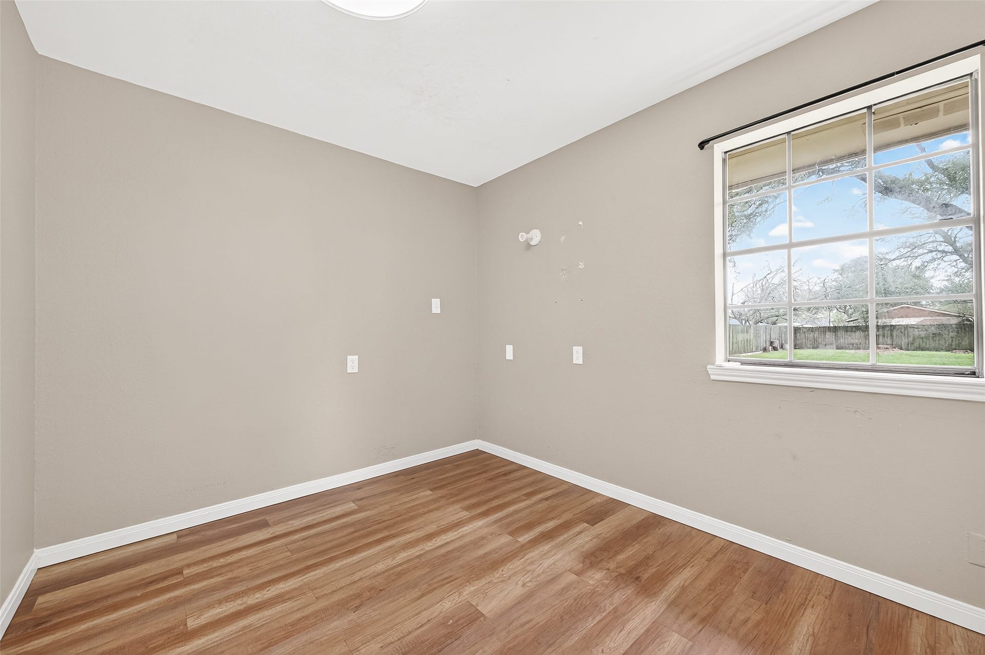 5607 Avenue M 1/2, Santa Fe, TX 77510 This room features neutral walls, wood flooring, and a large window offering plenty of natural light with a view of the backyard. Perfect for a small bedroom or home office.