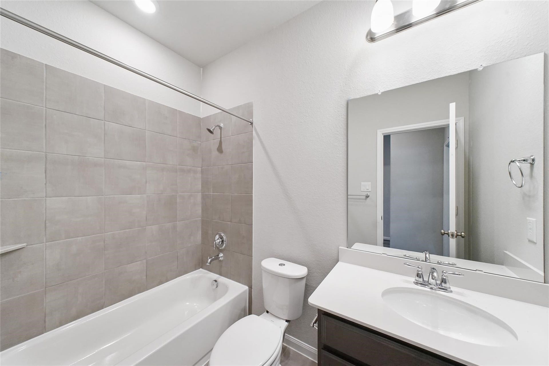Stylish full bathroom conveniently located near the secondary main floor bedroom, featuring a sleek vanity and a tiled shower/tub combo.