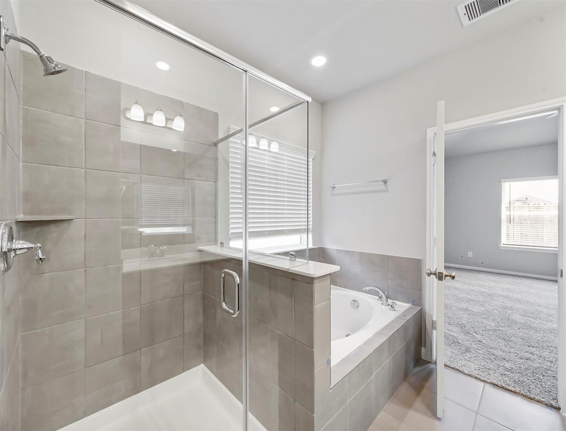 Enjoy ultimate relaxation in the glass-enclosed walk-in shower or unwind in the deep soaking tub with tile surround and ledge detail.