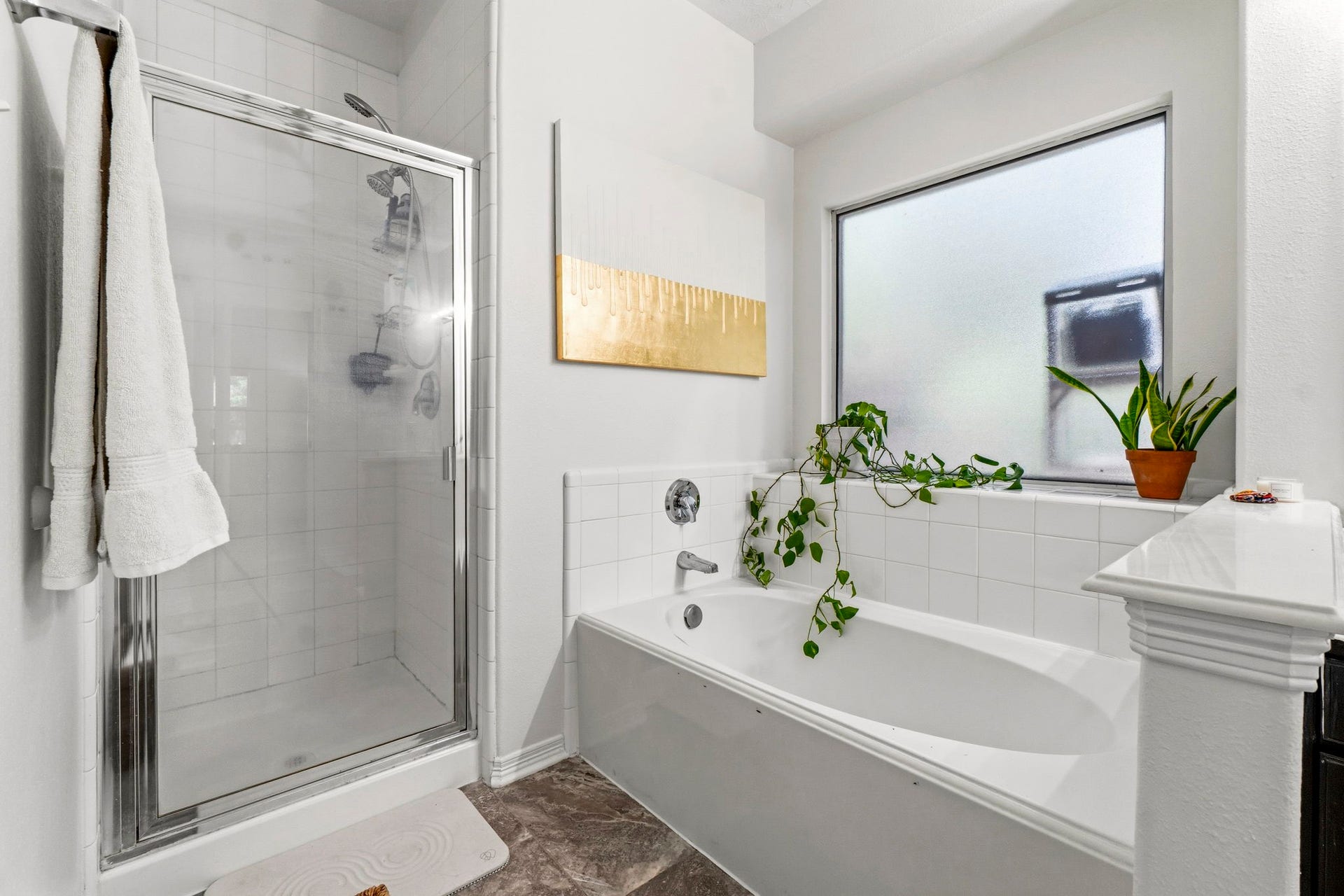 34019 Conroe Huffsmith Road, Magnolia, TX 77354 Bright, modern bathroom featuring a sleek glass shower, spacious bathtub, and ample natural light from a frosted window, complemented by elegant tile work and greenery.