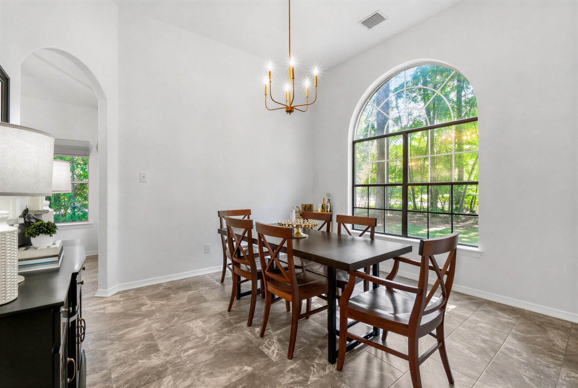 34019 Conroe Huffsmith Road, Magnolia, TX 77354 Bright dining area with a large arched window, elegant chandelier, and stylish tile flooring, perfect for entertaining.