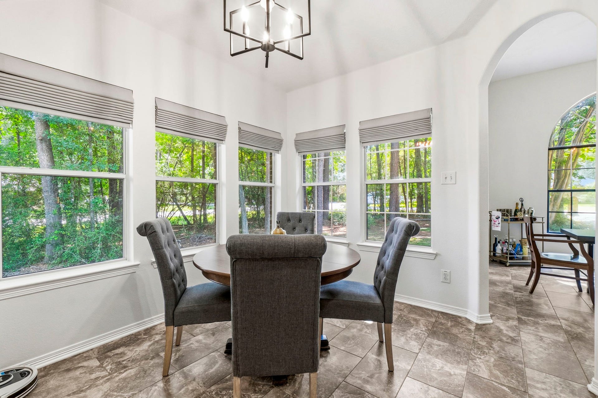 34019 Conroe Huffsmith Road, Magnolia, TX 77354 Bright dining area with large windows offering serene views of lush greenery, complemented by stylish tile flooring and modern lighting.
