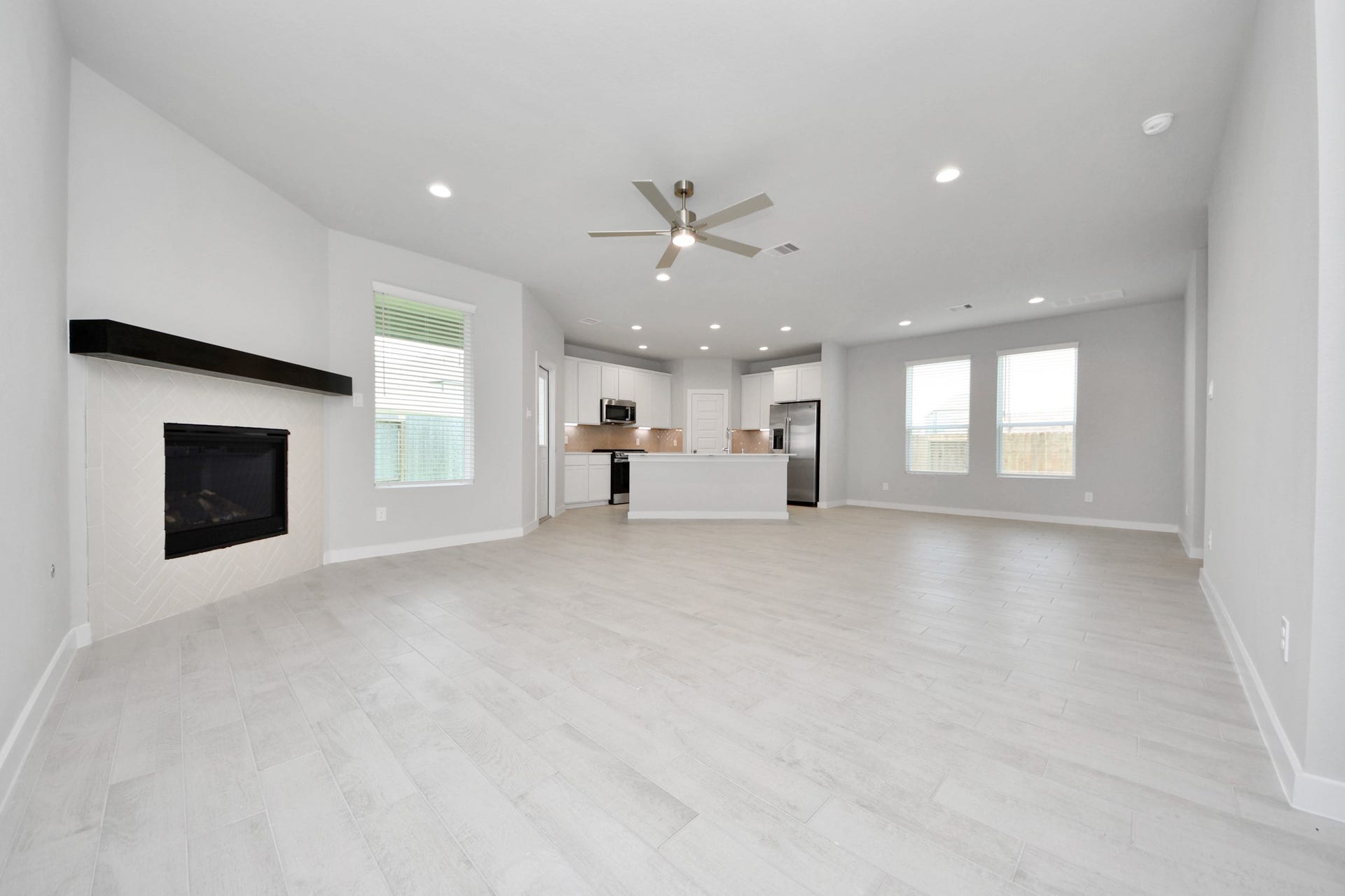 Welcome family and guests to your charming living room! With its high ceilings, recessed lighting, ceiling fan, custom paint, beautiful flooring, and large windows that let in abundant natural light, this room is perfect for gatherings. Sample photo of completed home with similar floor plan. Actual colors and selections may vary.