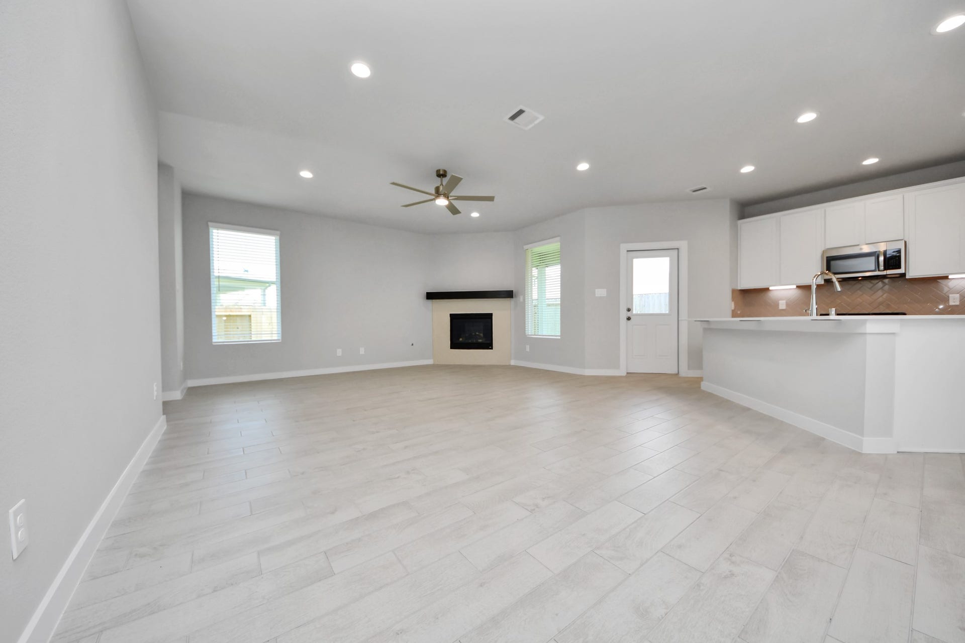 Relax and unwind in this inviting family room, illuminated by abundant natural light streaming in through tall windows, complemented by high ceilings and stunning flooring. Stay comfortable year-round with the gentle breeze from the ceiling fan, creating the perfect atmosphere for family gatherings. Sample photo of completed home with similar floor plan. Actual colors and selections may vary.