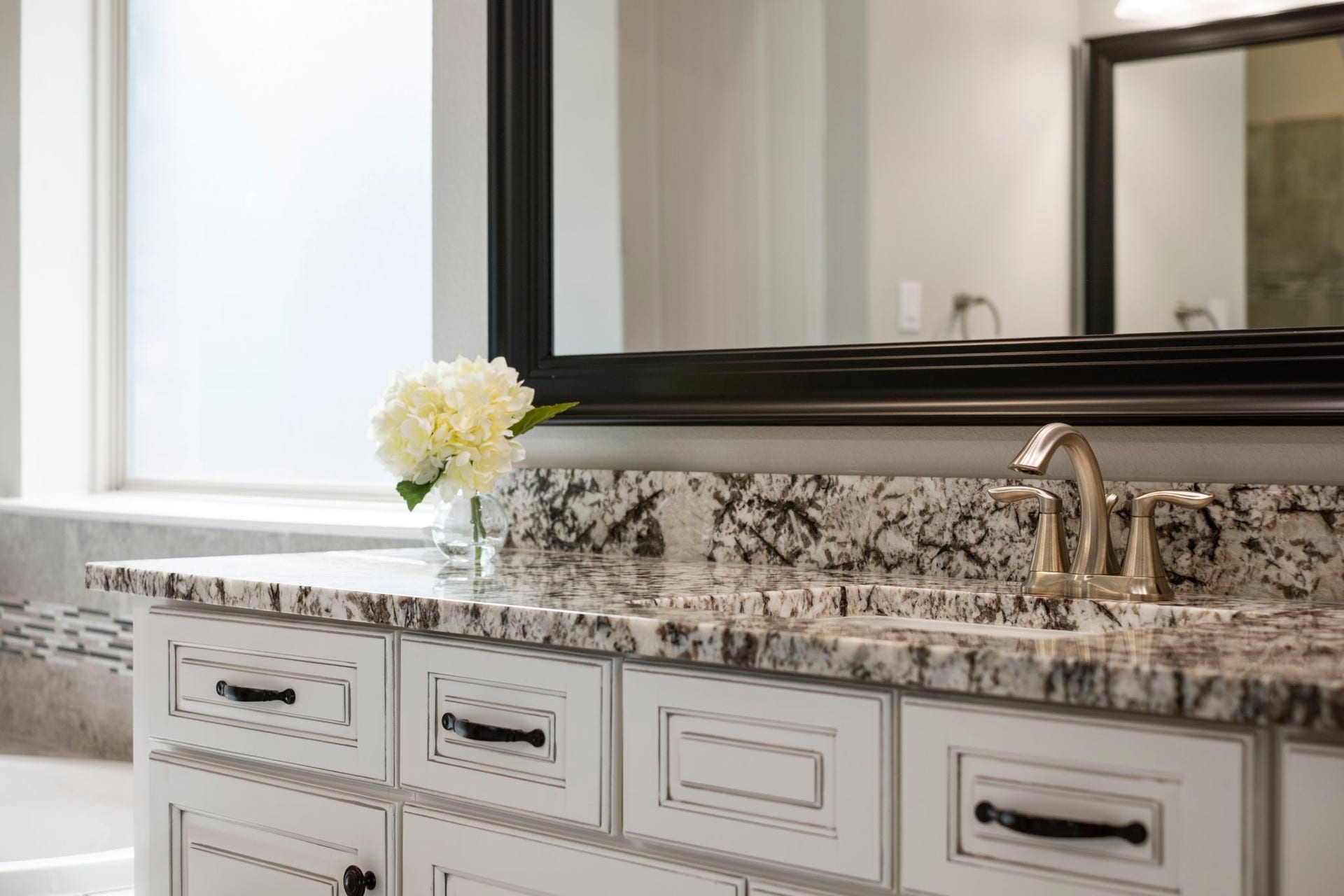 19314 Trotting Green Trail, Tomball, TX 77377 The primary ensuite bathroom complete with two vanities, french country cabinet finishes, granite countertops and brushed silver fixtures to complete the look