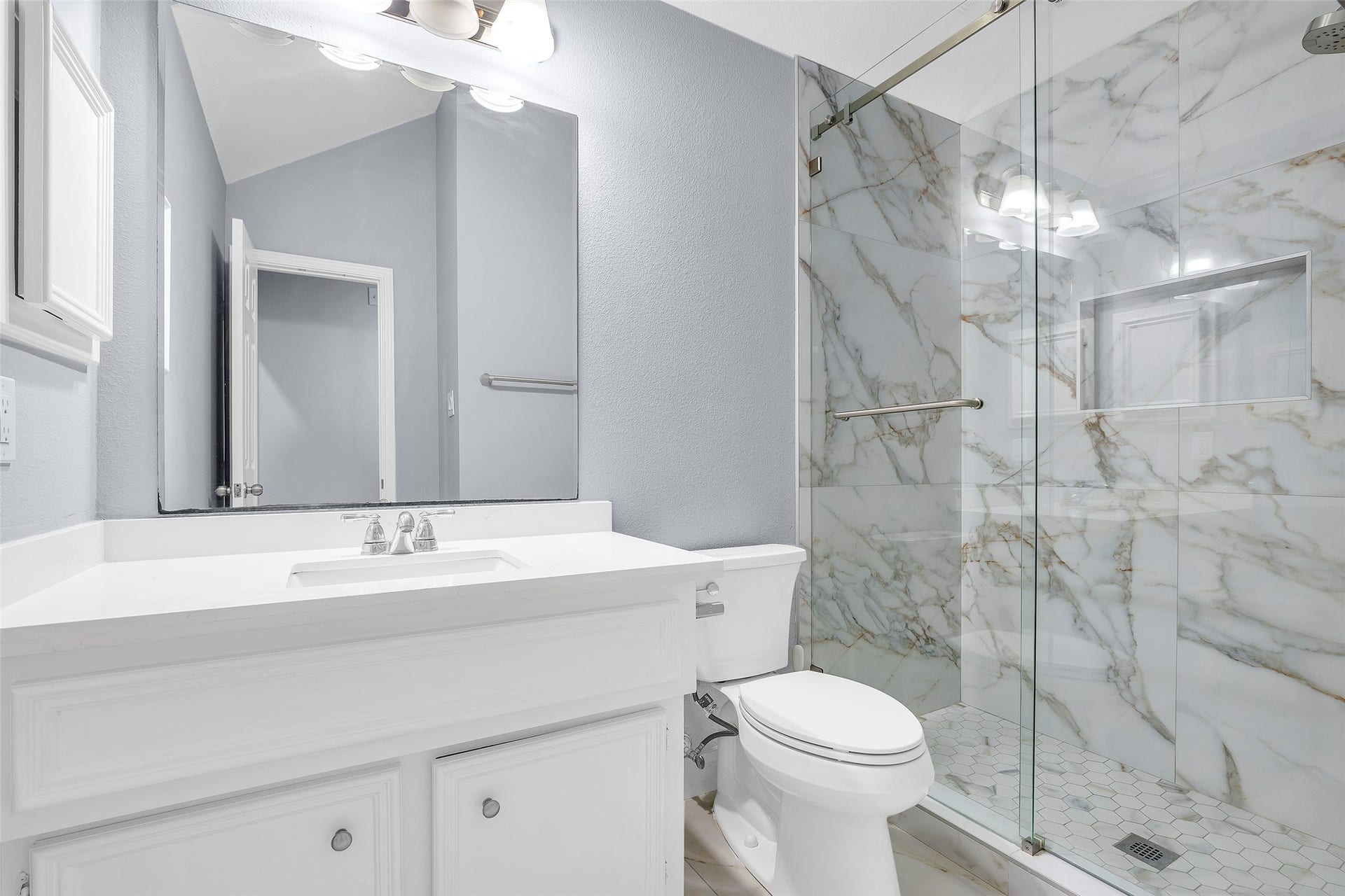10626 Cortland Ridge Lane, Cypress, TX 77433 Experience modern elegance in the second bathroom, featuring a sleek glass shower with luxurious marble-style tiles and a pristine white vanity.