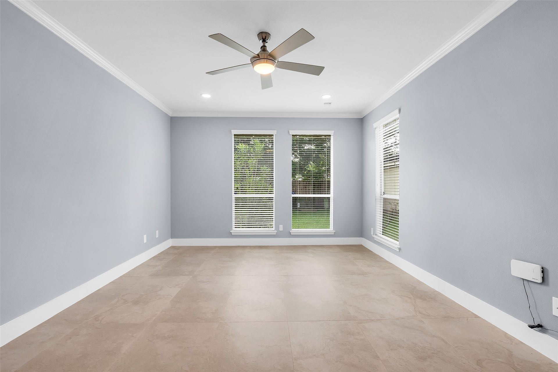 10626 Cortland Ridge Lane, Cypress, TX 77433 Experience tranquility in this expansive primary suite, featuring soft gray walls, oversized tile flooring, and abundant natural light through large windows.