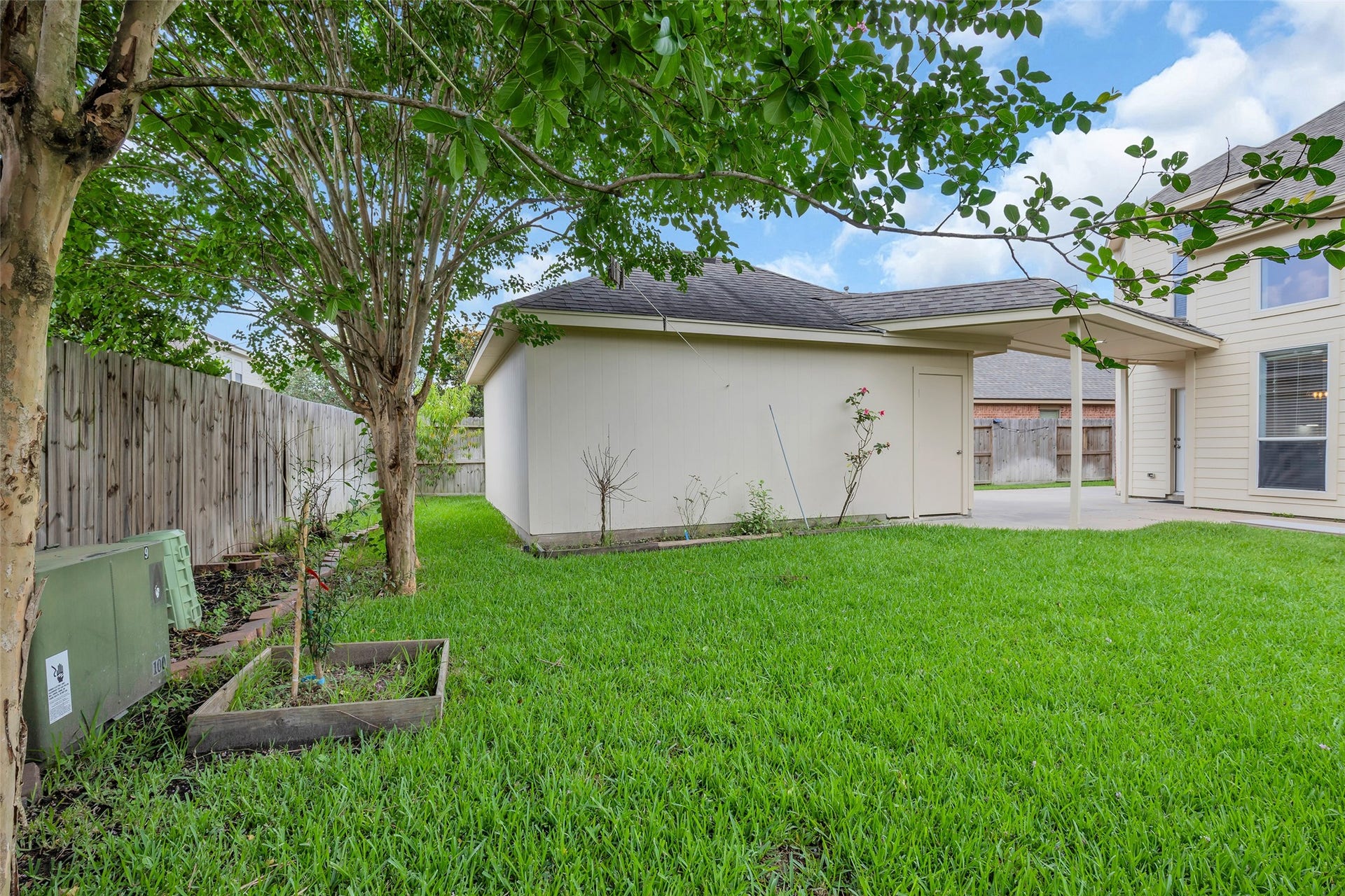 10626 Cortland Ridge Lane, Cypress, TX 77433 Charming backyard with lush green lawn, mature trees, and a cozy patio area perfect for outdoor gatherings.