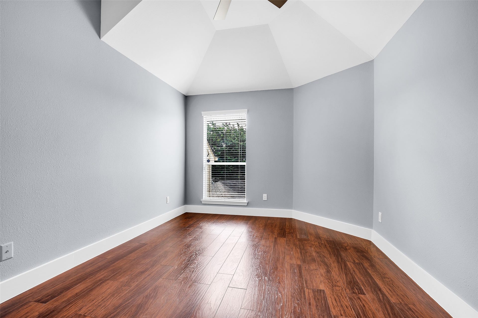 10626 Cortland Ridge Lane, Cypress, TX 77433 Experience comfort and style in this inviting second bedroom, featuring rich hardwood floors, soft gray walls, and a vaulted ceiling that enhances the airy ambiance.