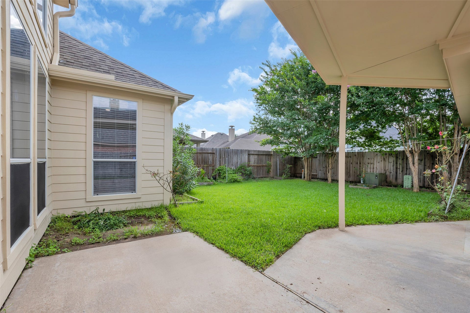 10626 Cortland Ridge Lane, Cypress, TX 77433 Charming backyard with a covered patio, lush green lawn, and privacy fence, perfect for outdoor relaxation and gatherings.
