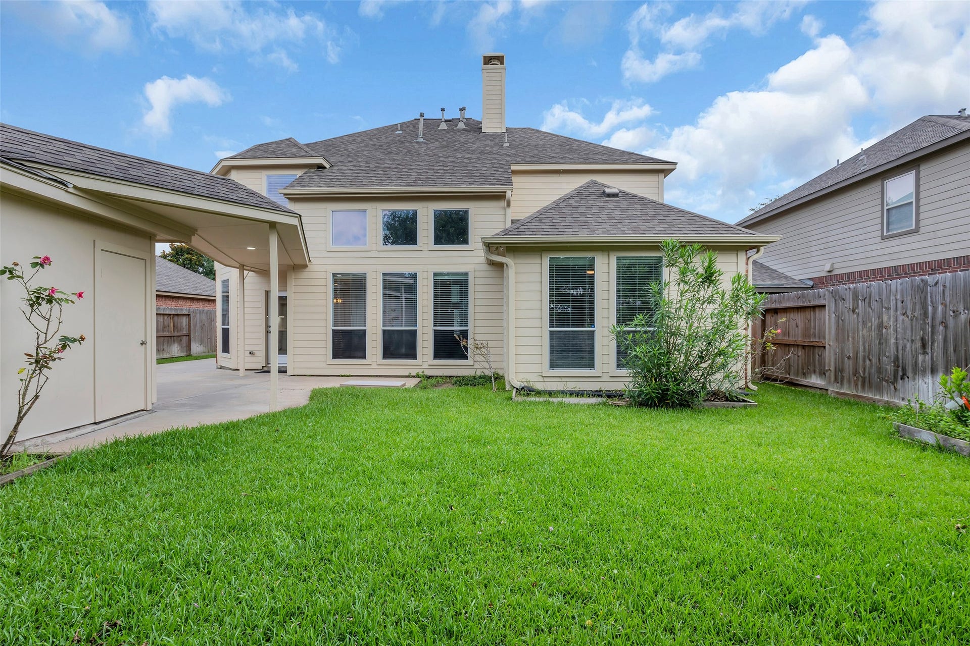 10626 Cortland Ridge Lane, Cypress, TX 77433 Spacious backyard with lush green lawn, bordered by a wooden fence for privacy, and a charming exterior featuring large windows for ample natural light.