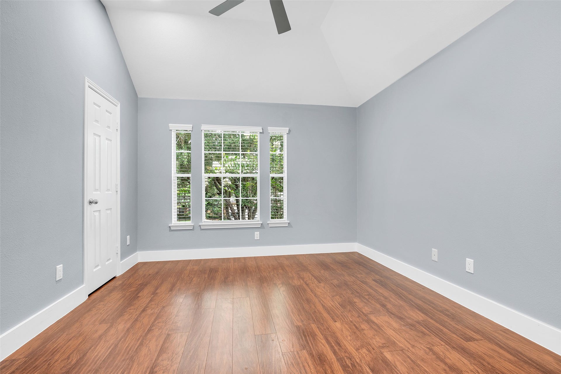 10626 Cortland Ridge Lane, Cypress, TX 77433 Experience tranquility in the first bedroom, featuring elegant wood flooring, soft gray walls, and abundant natural light from generous windows.
