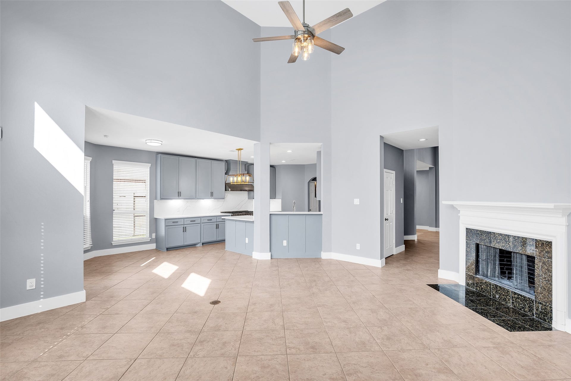 10626 Cortland Ridge Lane, Cypress, TX 77433 Spacious open-concept living area with high ceilings, featuring a modern kitchen with gray cabinetry and a cozy fireplace, all bathed in natural light.