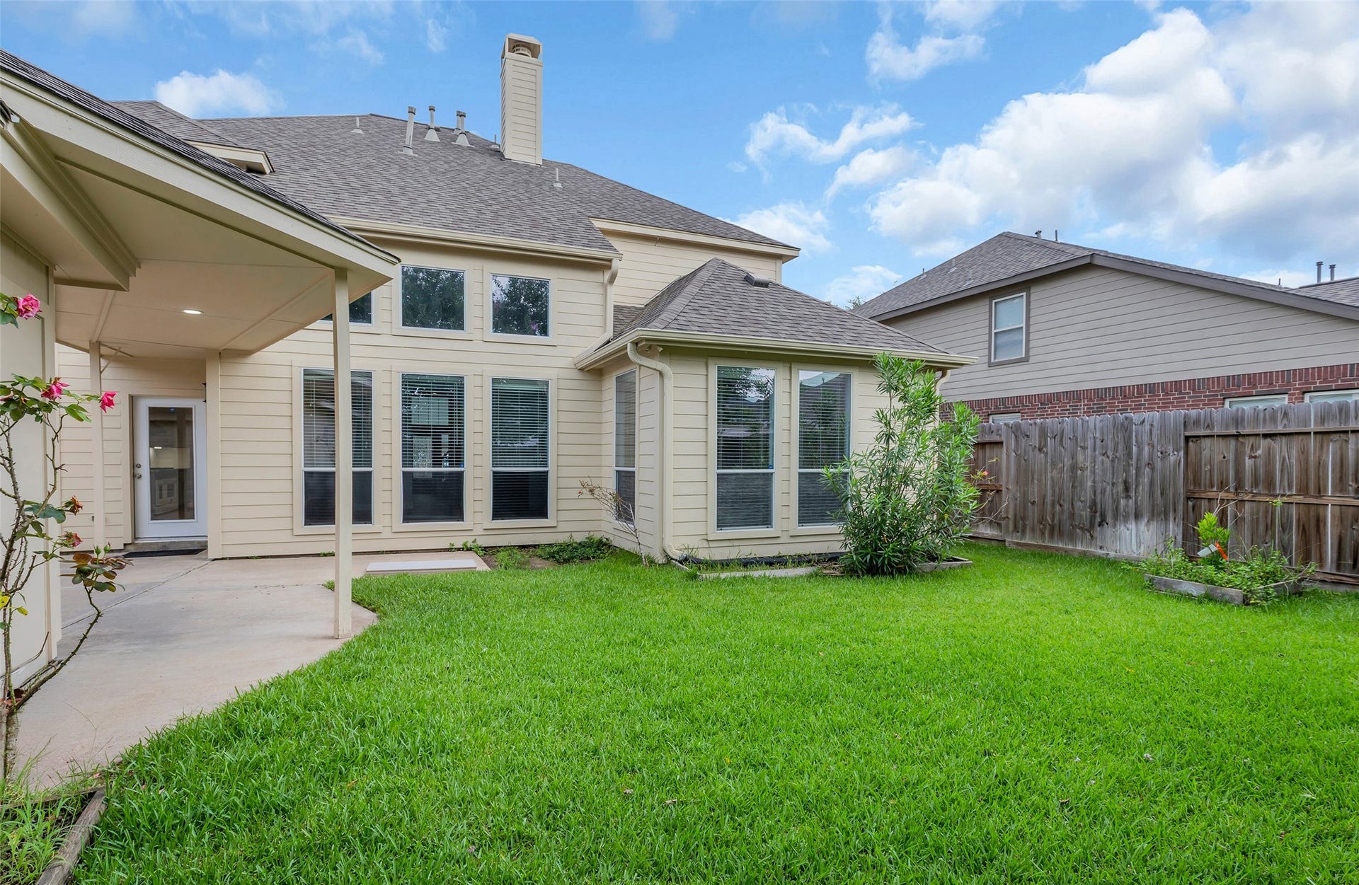 10626 Cortland Ridge Lane, Cypress, TX 77433 Charming backyard with lush green lawn, a cozy covered patio, and ample windows for natural light, perfect for relaxation and outdoor gatherings.