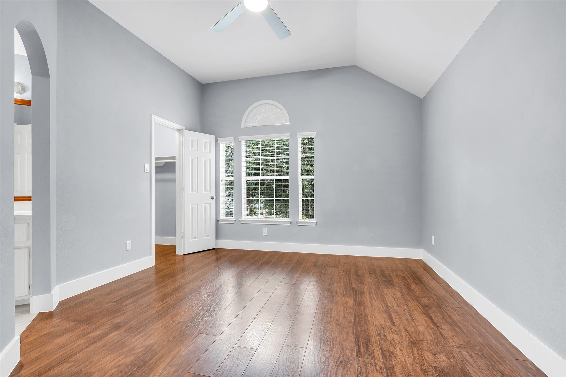 10626 Cortland Ridge Lane, Cypress, TX 77433 The third bedroom offers a bright and inviting space with elegant wood floors, a charming arched window, and a vaulted ceiling, perfect for relaxation or a creative retreat.