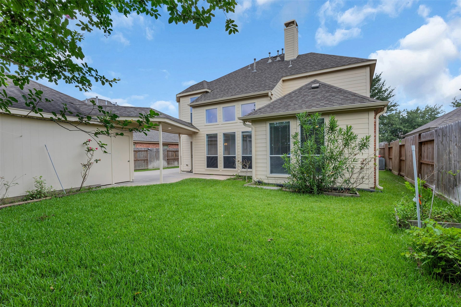 10626 Cortland Ridge Lane, Cypress, TX 77433 Charming backyard with lush green lawn, a cozy covered patio, and ample space for outdoor activities, nestled behind a beautiful two-story home.