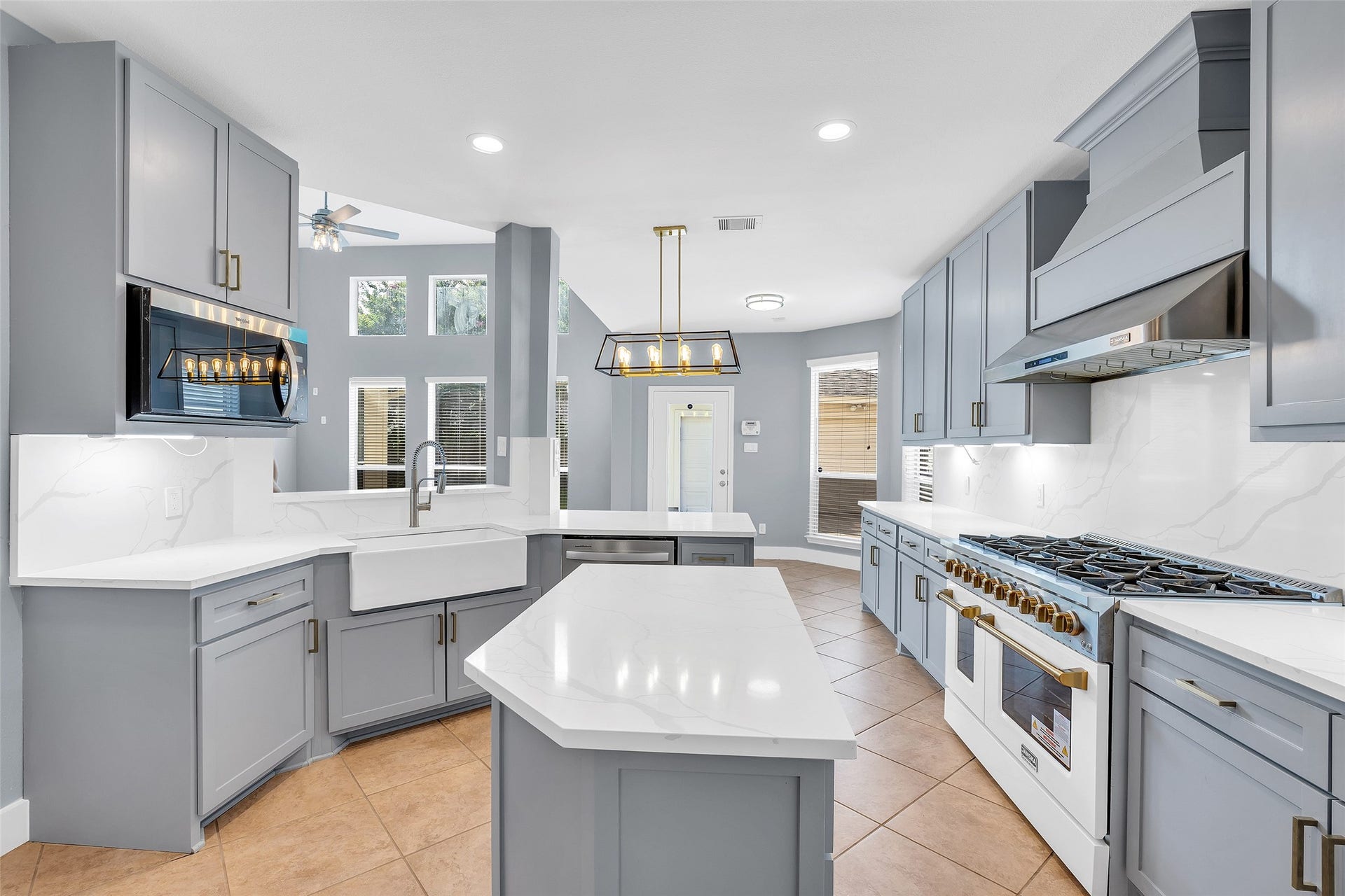 10626 Cortland Ridge Lane, Cypress, TX 77433 A spacious, modern kitchen with sleek gray cabinetry, quartz countertops, and top-of-the-line stainless steel appliances. The large island and farmhouse sink add functionality and style, complemented by stylish pendant lighting.