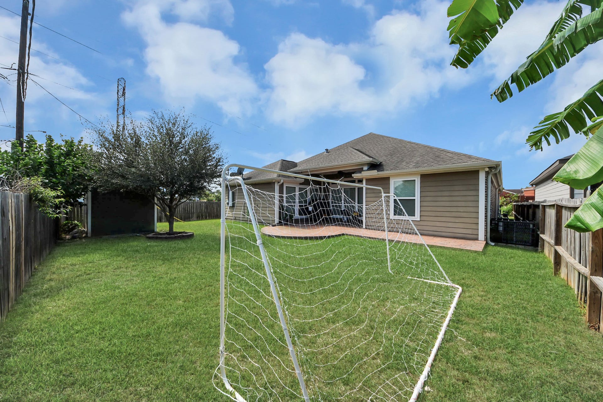 Backyard lawn with a view of the home and covered patio.