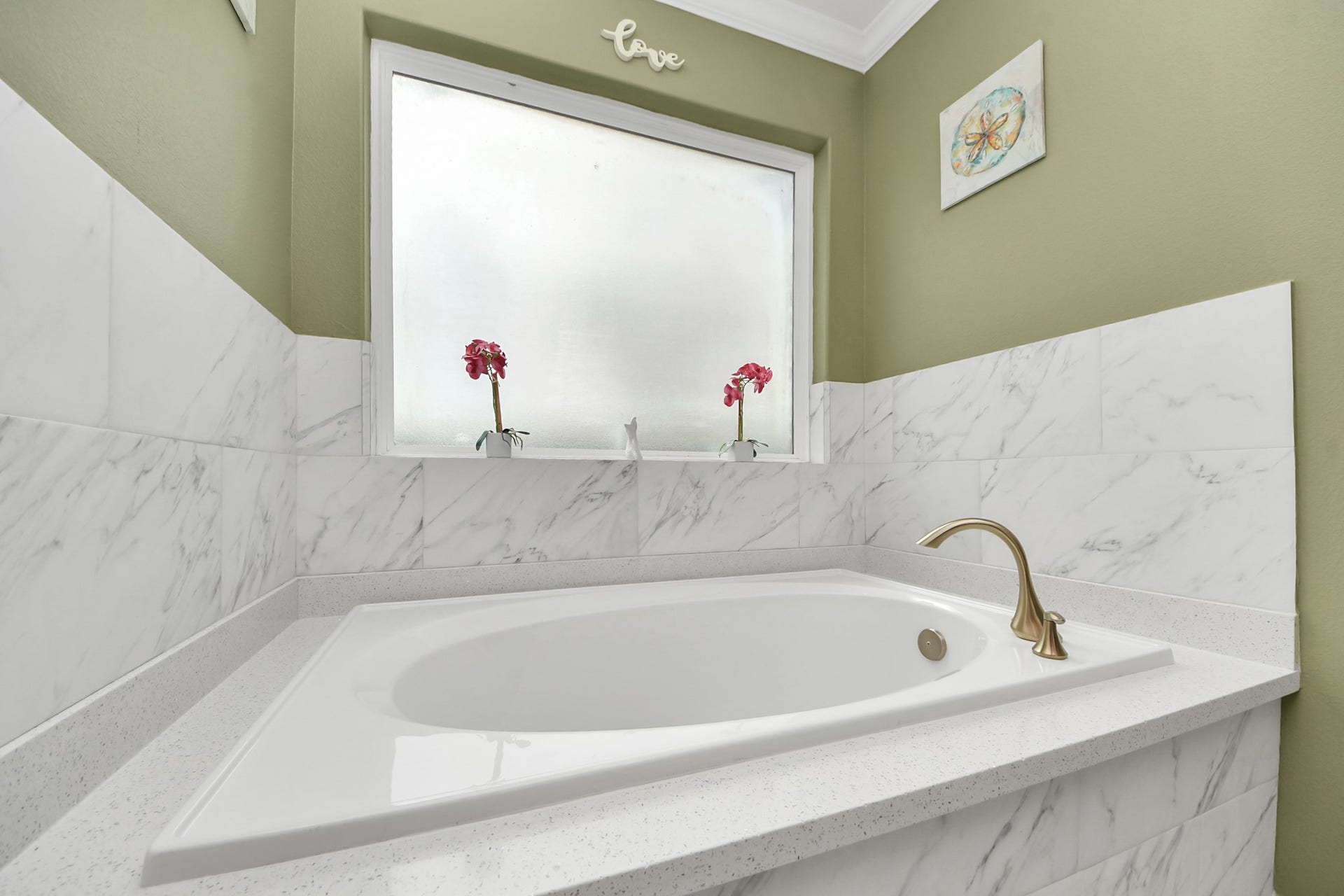 Corner soaking tub beneath a window in the primary bathroom.