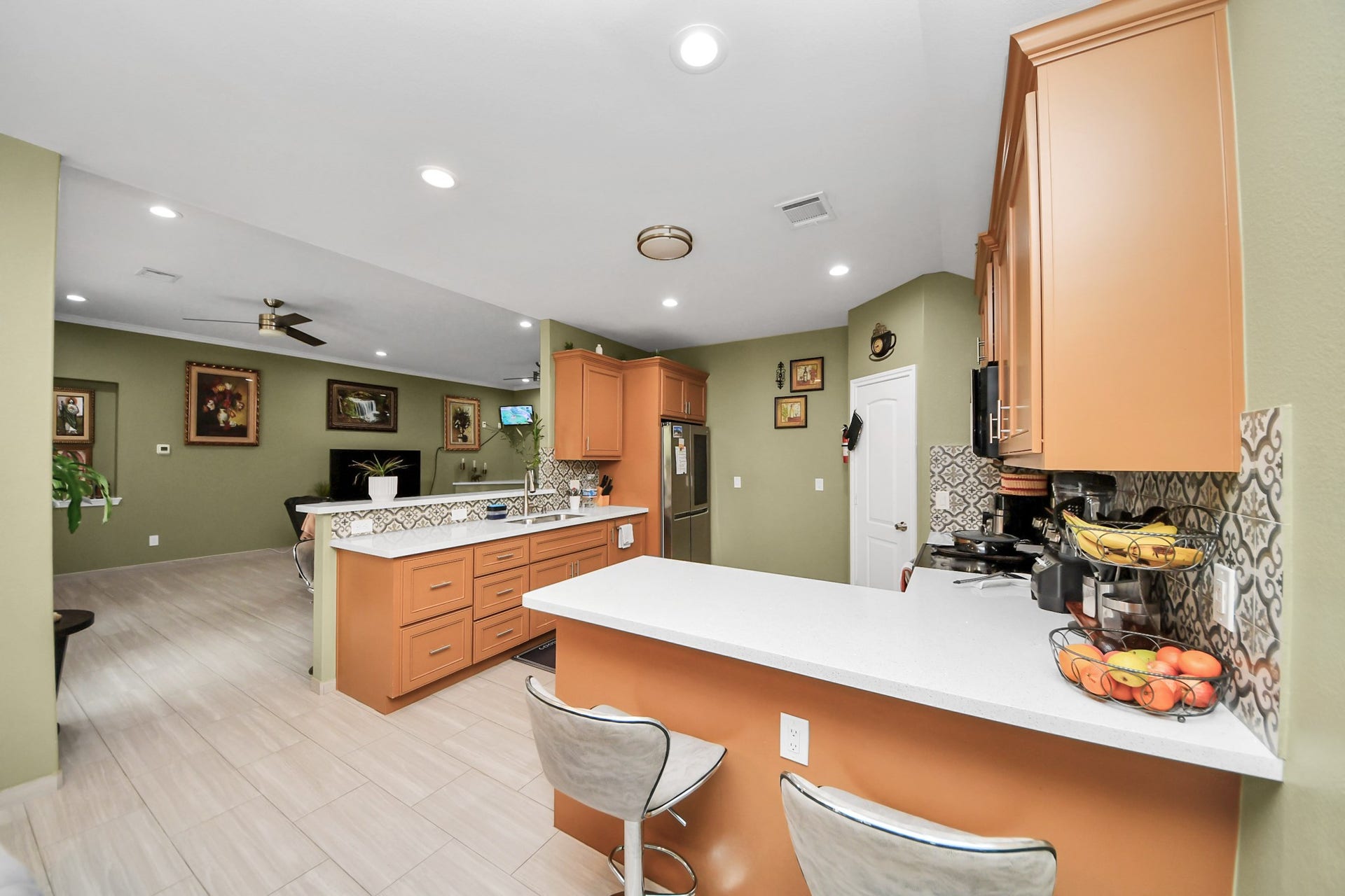 Kitchen counter space and wood cabinets frame the breakfast bar.