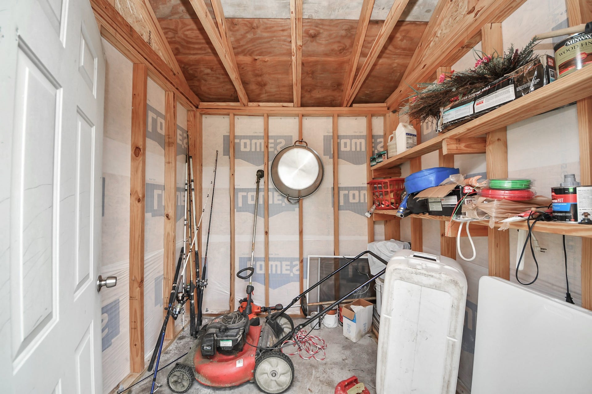 Garage interior with wall shelving and overhead storage space.