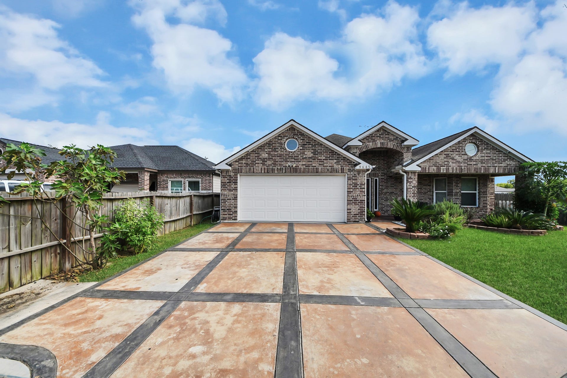 Decorative driveway accents lead to the attached garage.