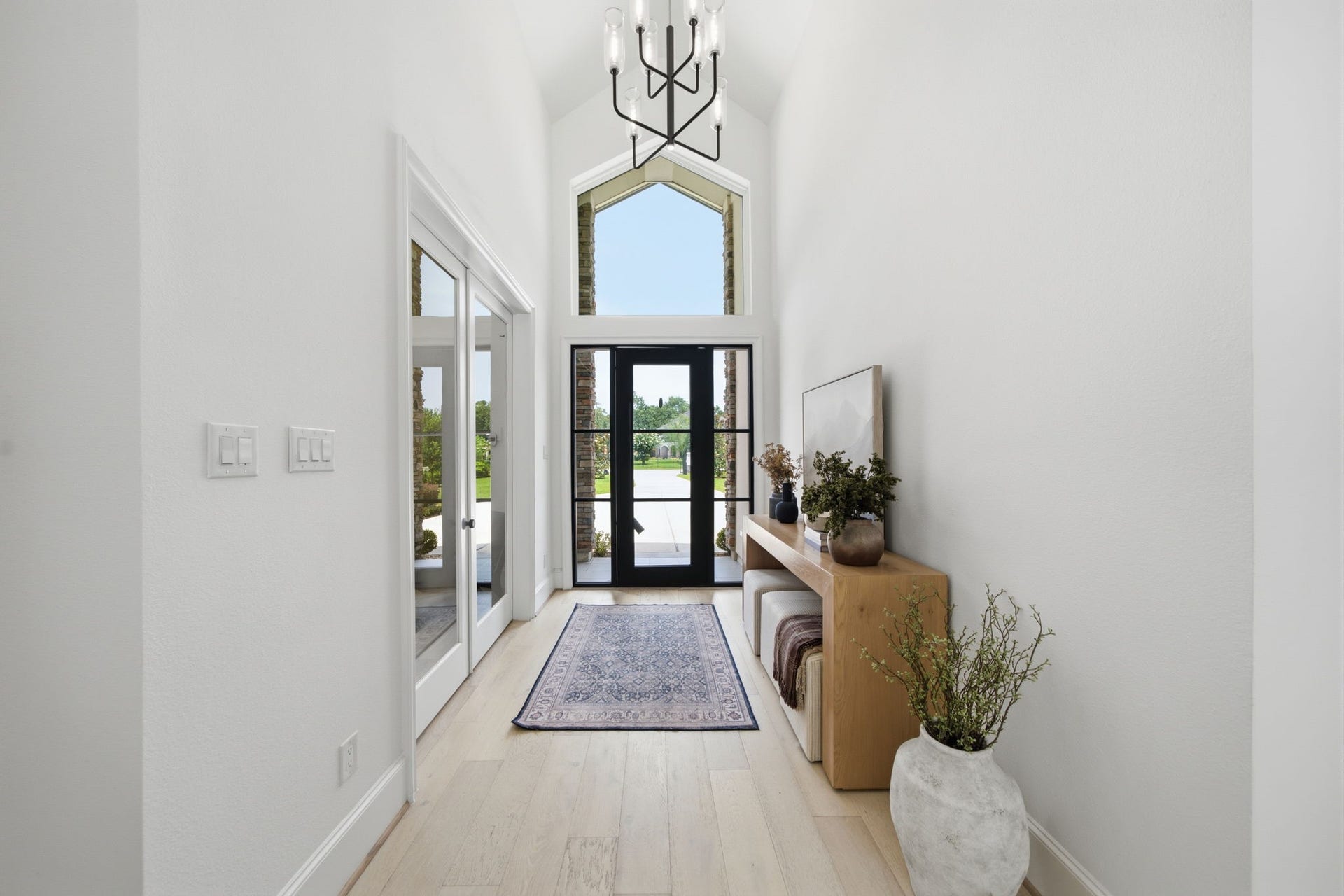 6310 Star Light Court, Spring, TX 77386 Bright and welcoming entryway featuring high ceilings, a modern chandelier, and large glass doors that flood the space with natural light, complemented by stylish decor and a neutral color palette.