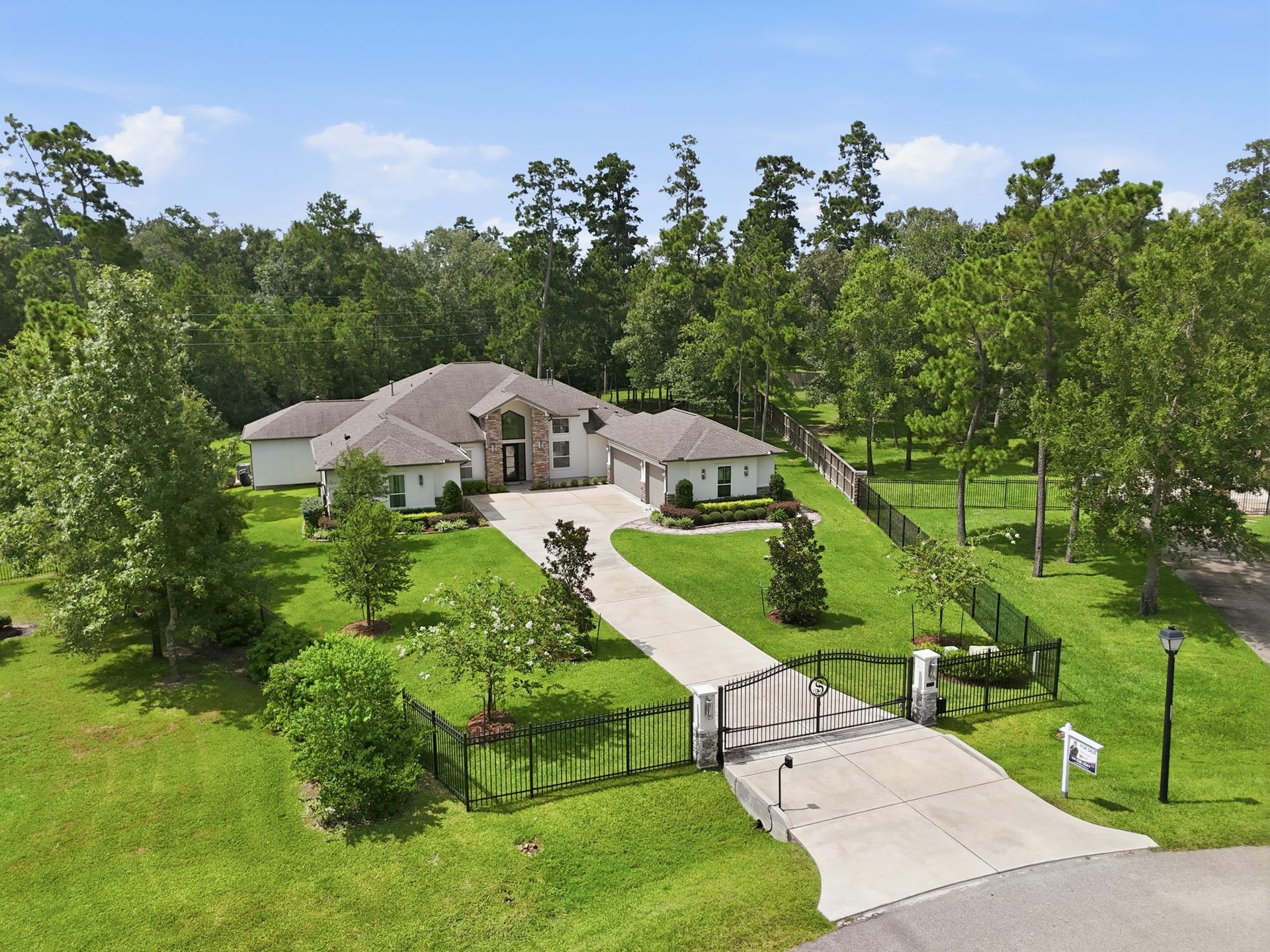 6310 Star Light Court, Spring, TX 77386 Stunning gated estate on a spacious, lush green lot with a long driveway leading to a charming single-story home surrounded by mature trees for ultimate privacy.