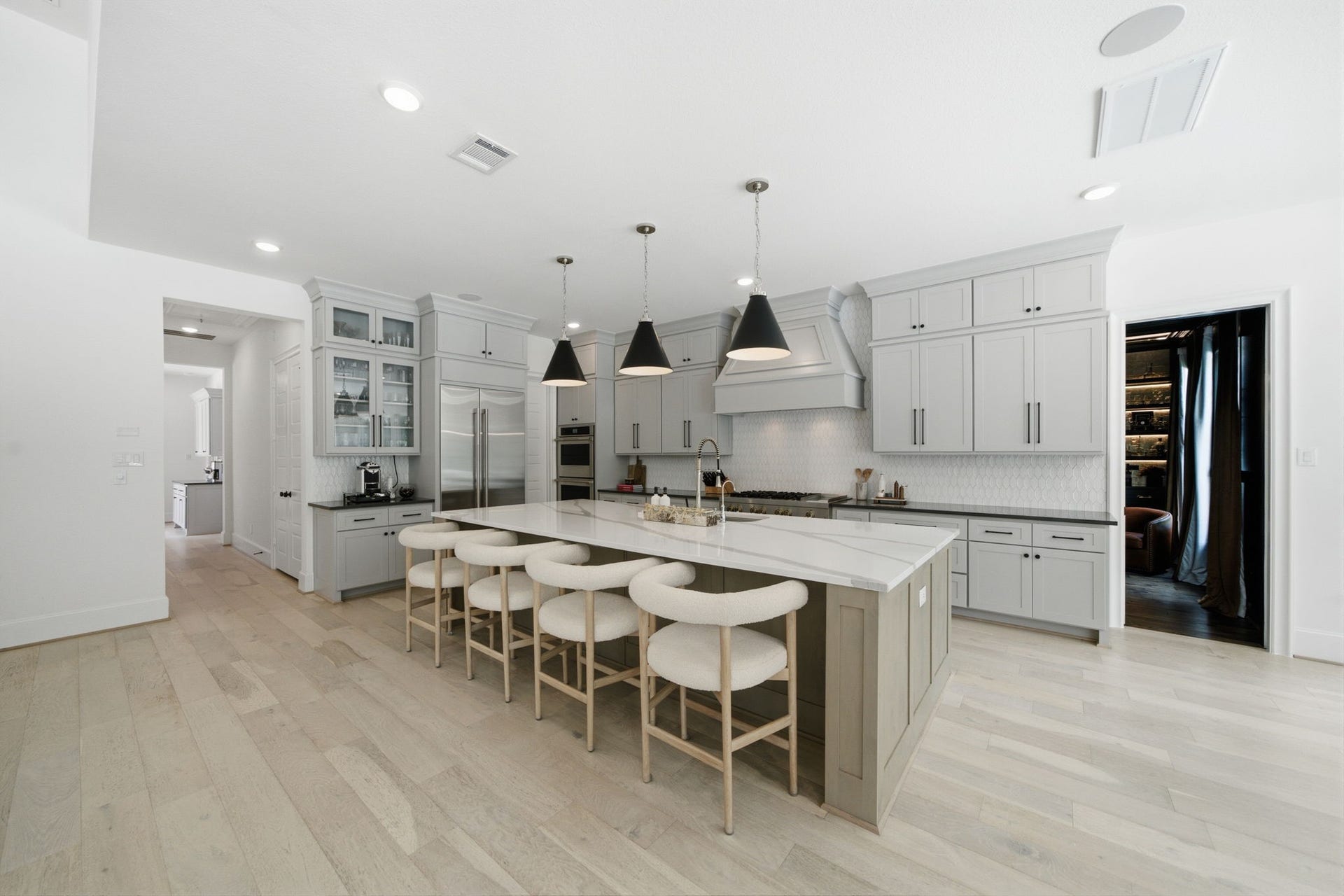 6310 Star Light Court, Spring, TX 77386 Spacious modern kitchen with sleek gray cabinetry, a large central island featuring elegant pendant lighting, and high-end stainless steel appliances.